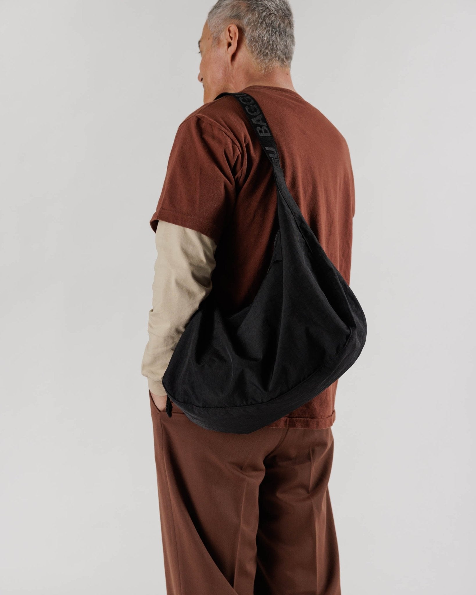 Man wearing the large black crescent bag on shoulder - ANNIE.G
