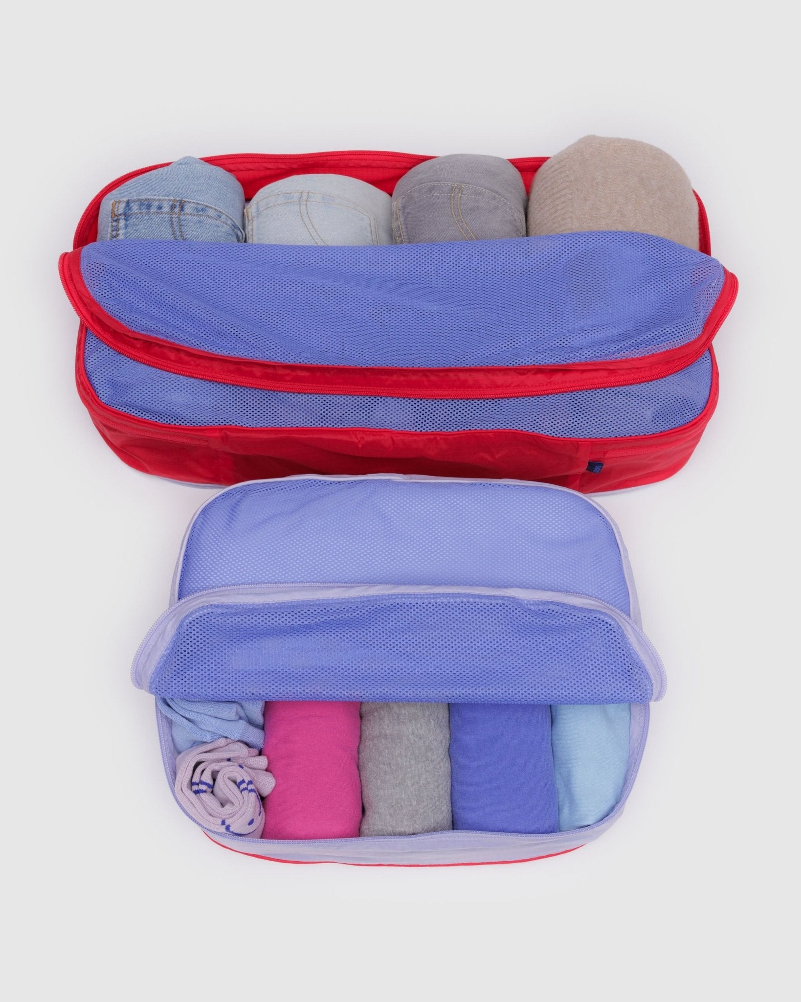 Two storage bags, a red and a purple, filled with clothes and mesh zip top folded back.
