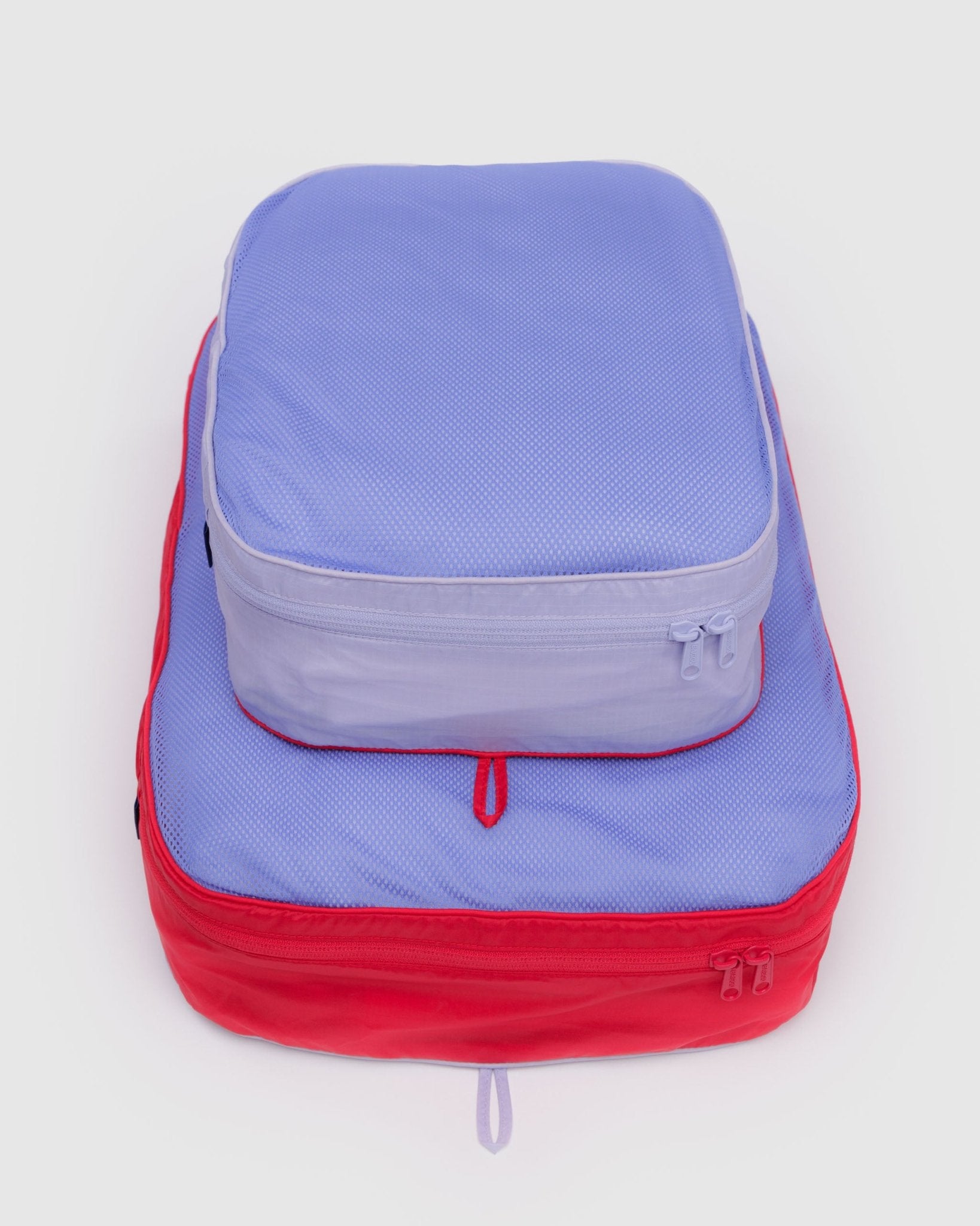 Set of two large size stacked, zippered packing cubes with mesh top, in red and purple, with hanging loops.