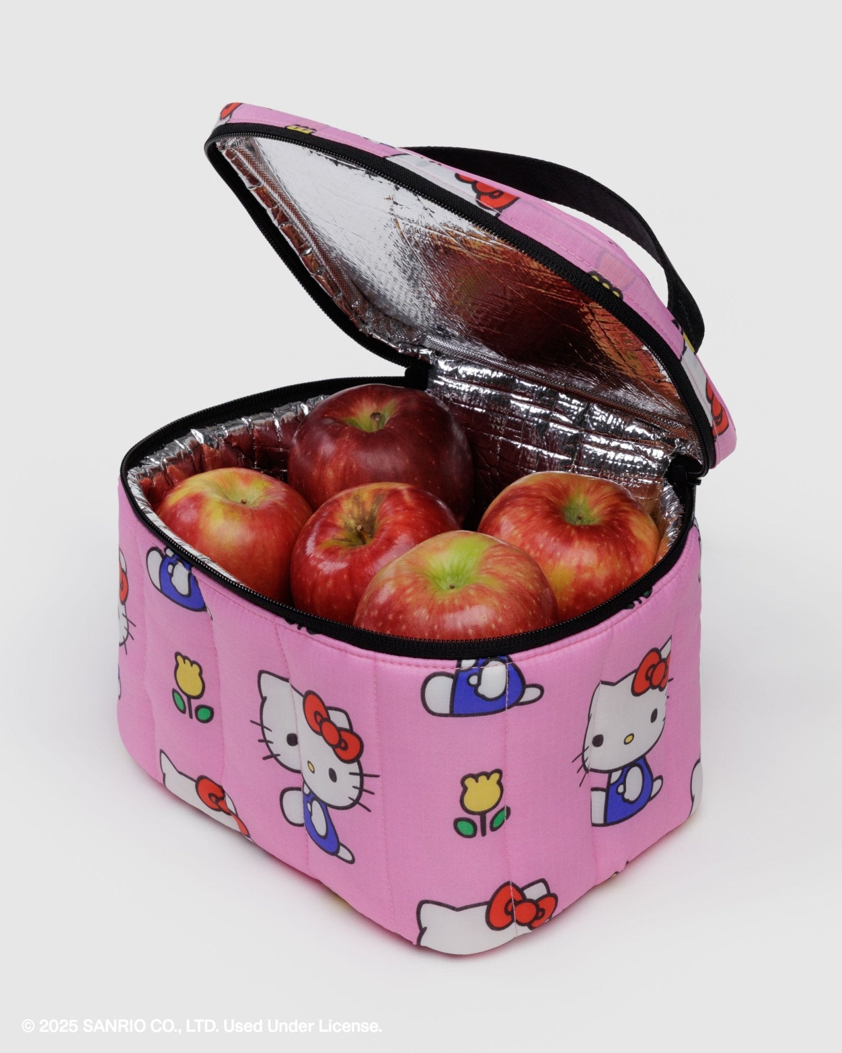 Pink insulated lunch bag with Hello Kitty designs containing red apples and zip top lid open and black carry handle