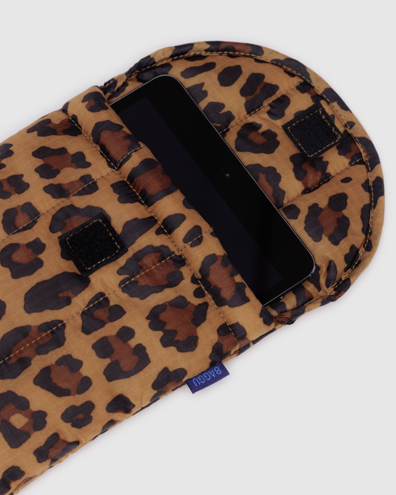 Tablet inside a leopard print on puffy quilted tablet sleeve with Baggu tag at the side and velcro closure at top - ANNIE.G