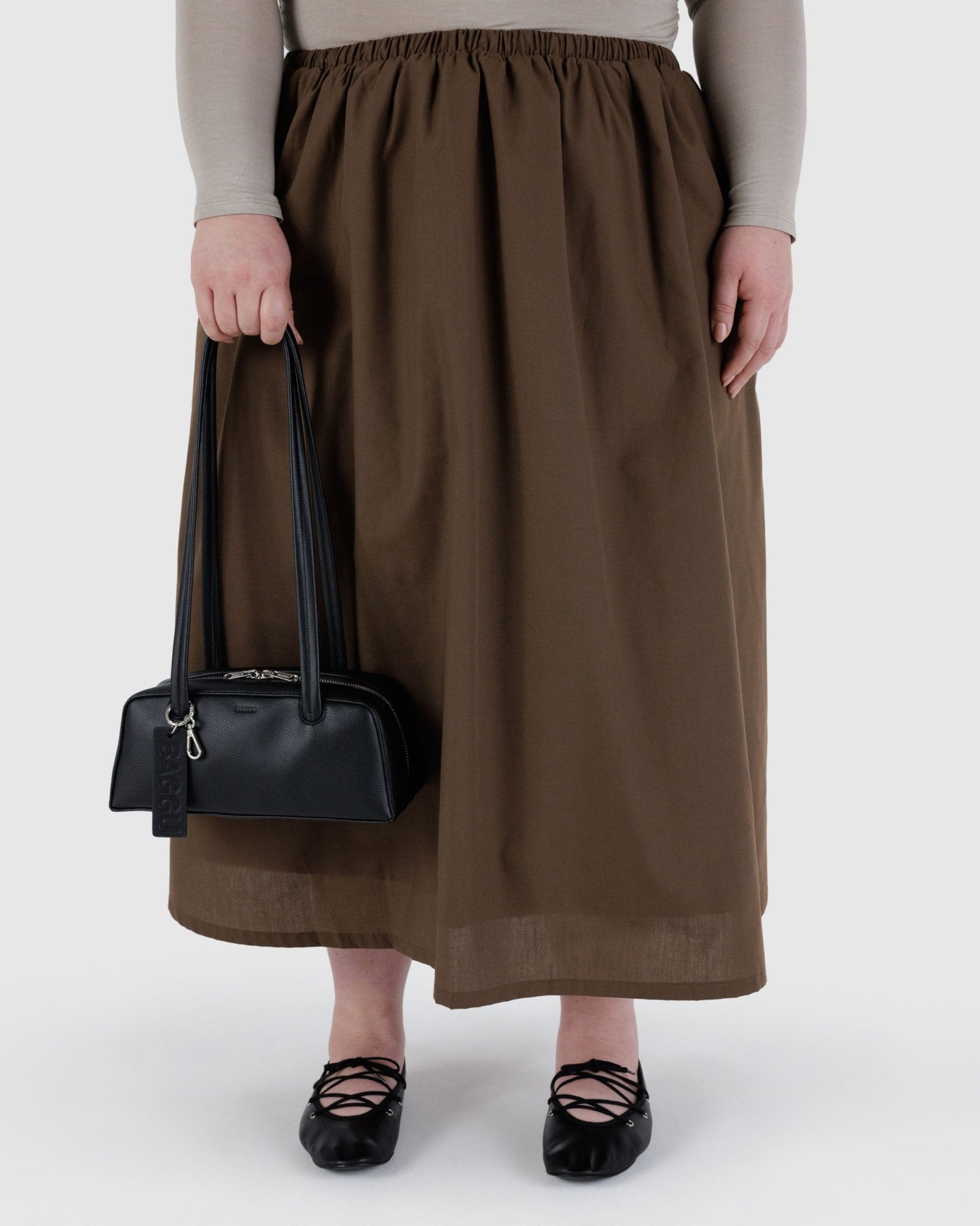 Woman holding a small black leather bowler bag. with metal clip and double zips.