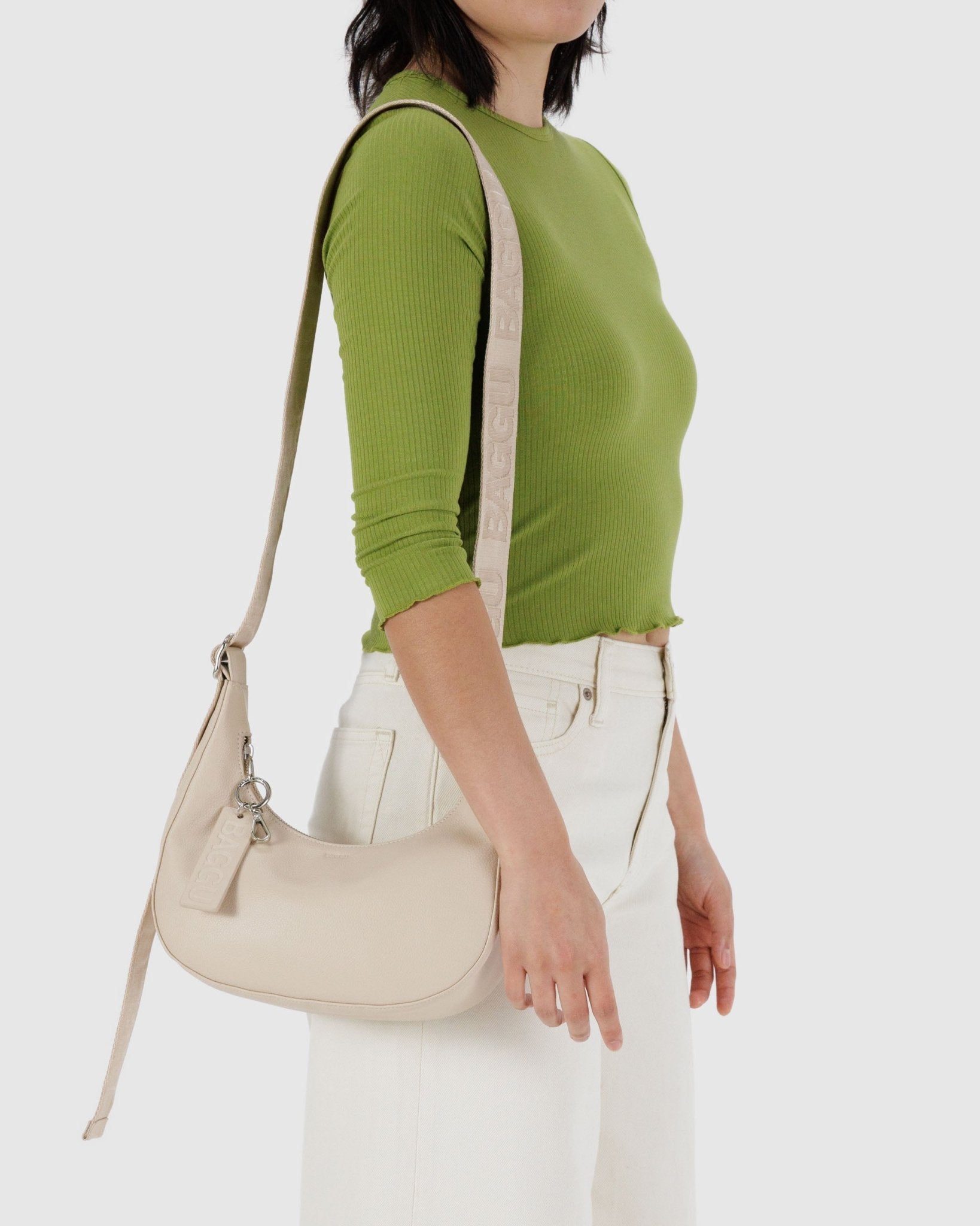 Woman carrying a stone coloured Small Recycled Leather Crescent Bag on shoulder.