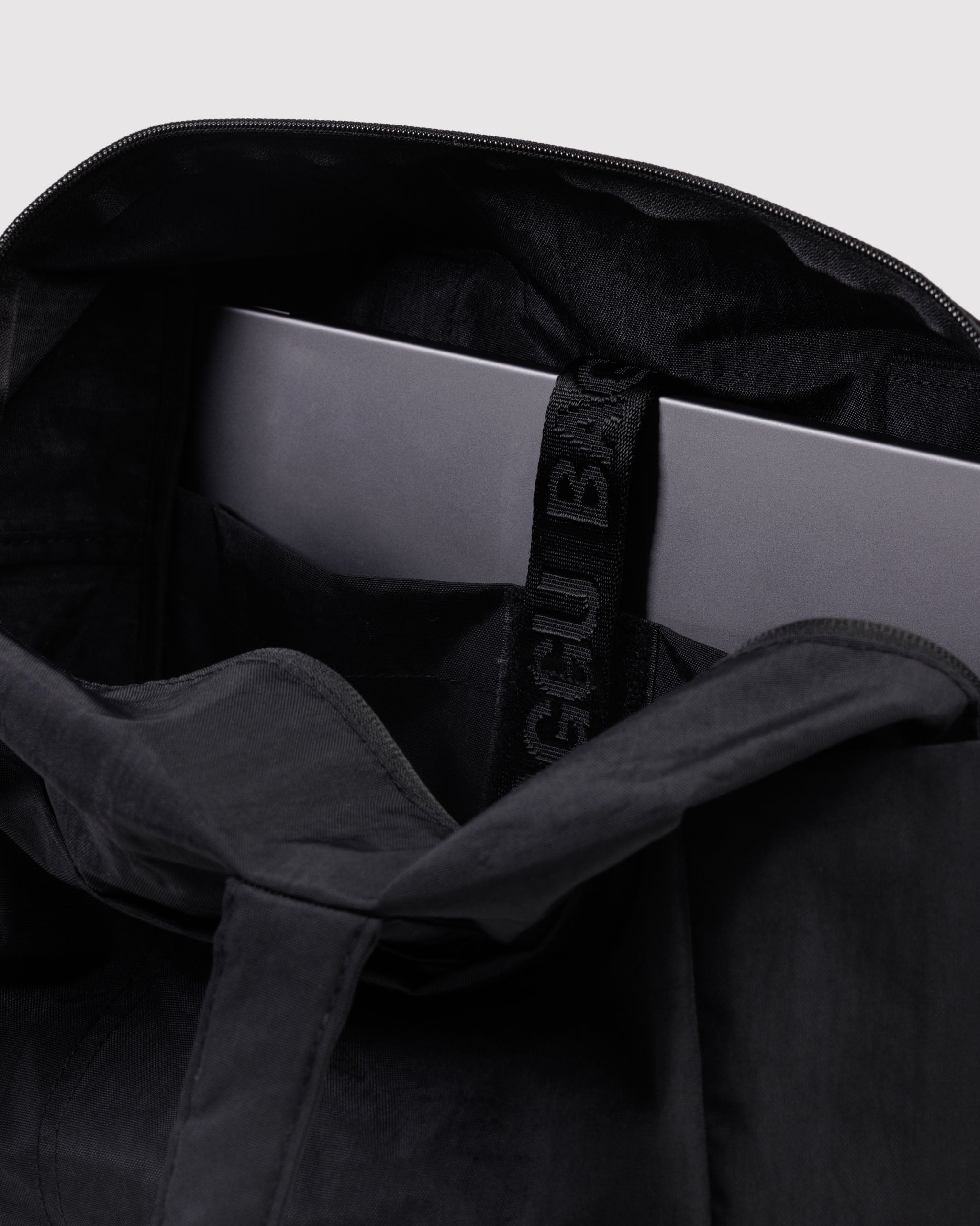 Black handbag with a laptop inside a tech pocket with secure strap.