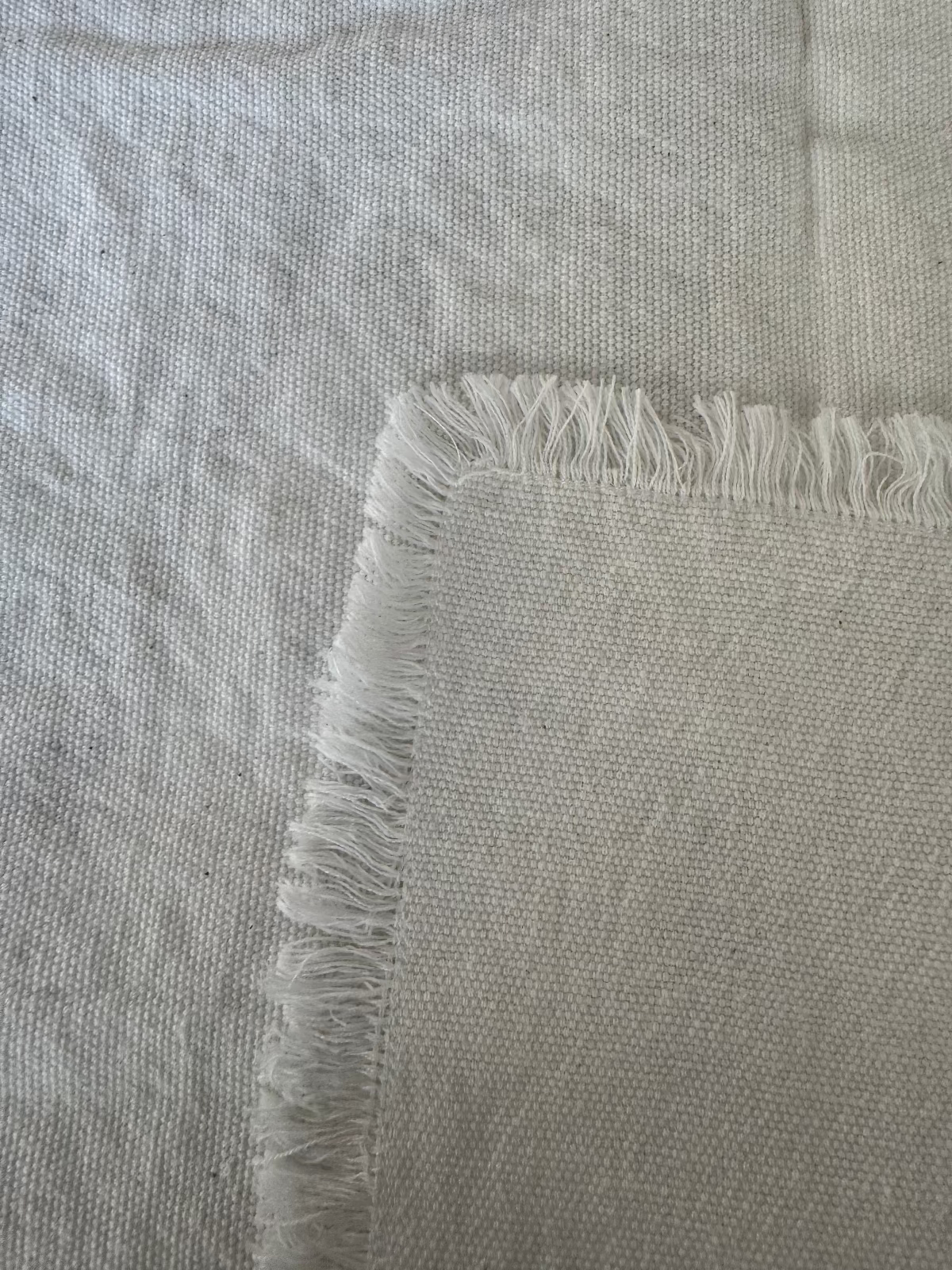 Close-up of a white cotton napkin with frayed edges