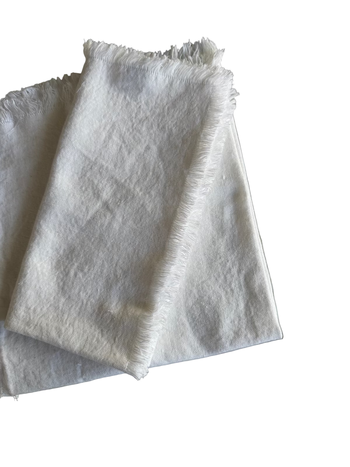 One white fabric napkin with a frayed edge folded on top of another white napkin