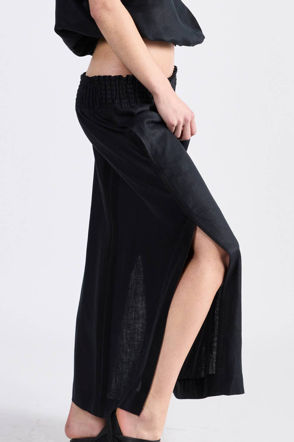 Woman wearing a black shirred waist skirt with side split in black - ANNIE.G