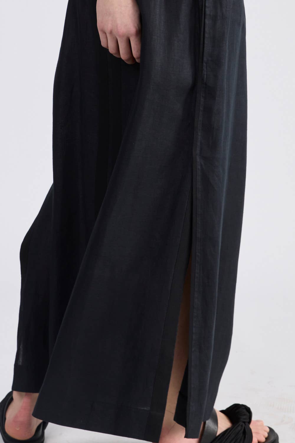 Close up of black maxi skirt side split.