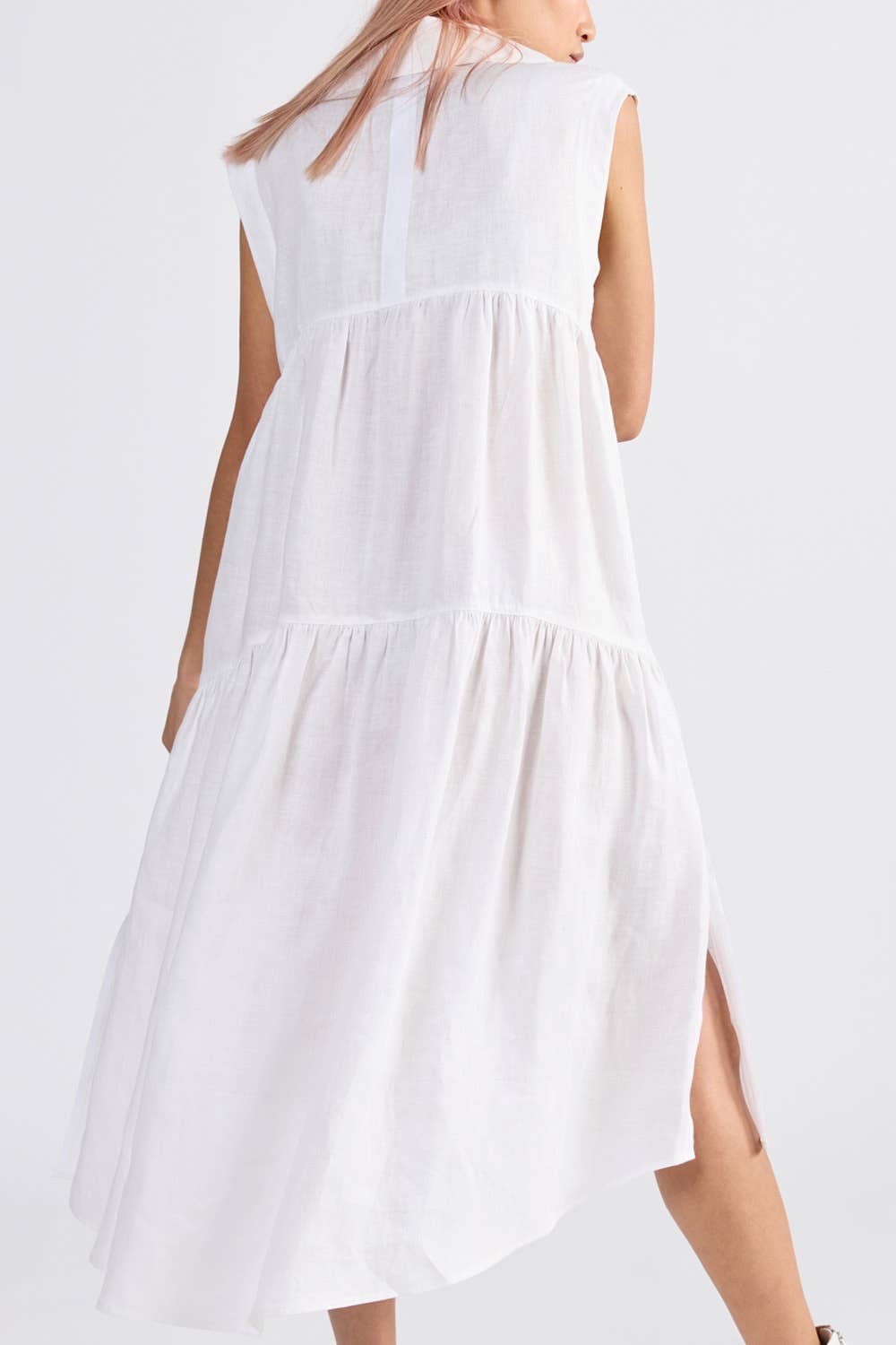 Back of a woman wearing an ivory sleeveless dress with side split - ANNIE.G