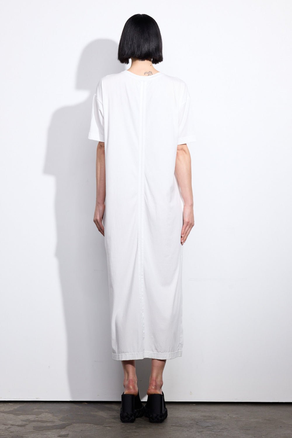 Back of a woman wearing a white t-shirt dress with two grosgrain ribbon stripes down the middle - ANNIE.G