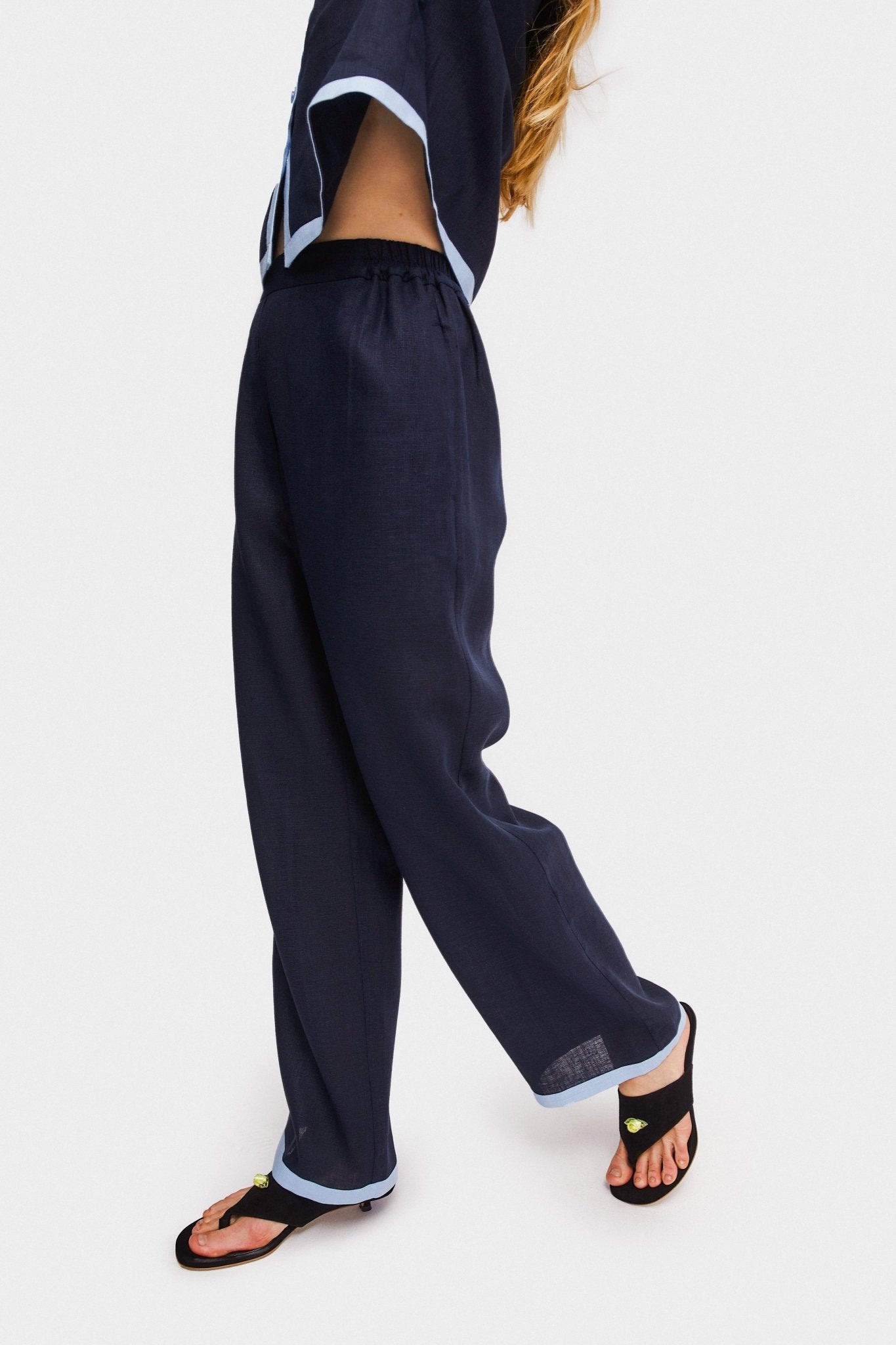 Woman with hands above head wearing navy shirt and matching long pants.