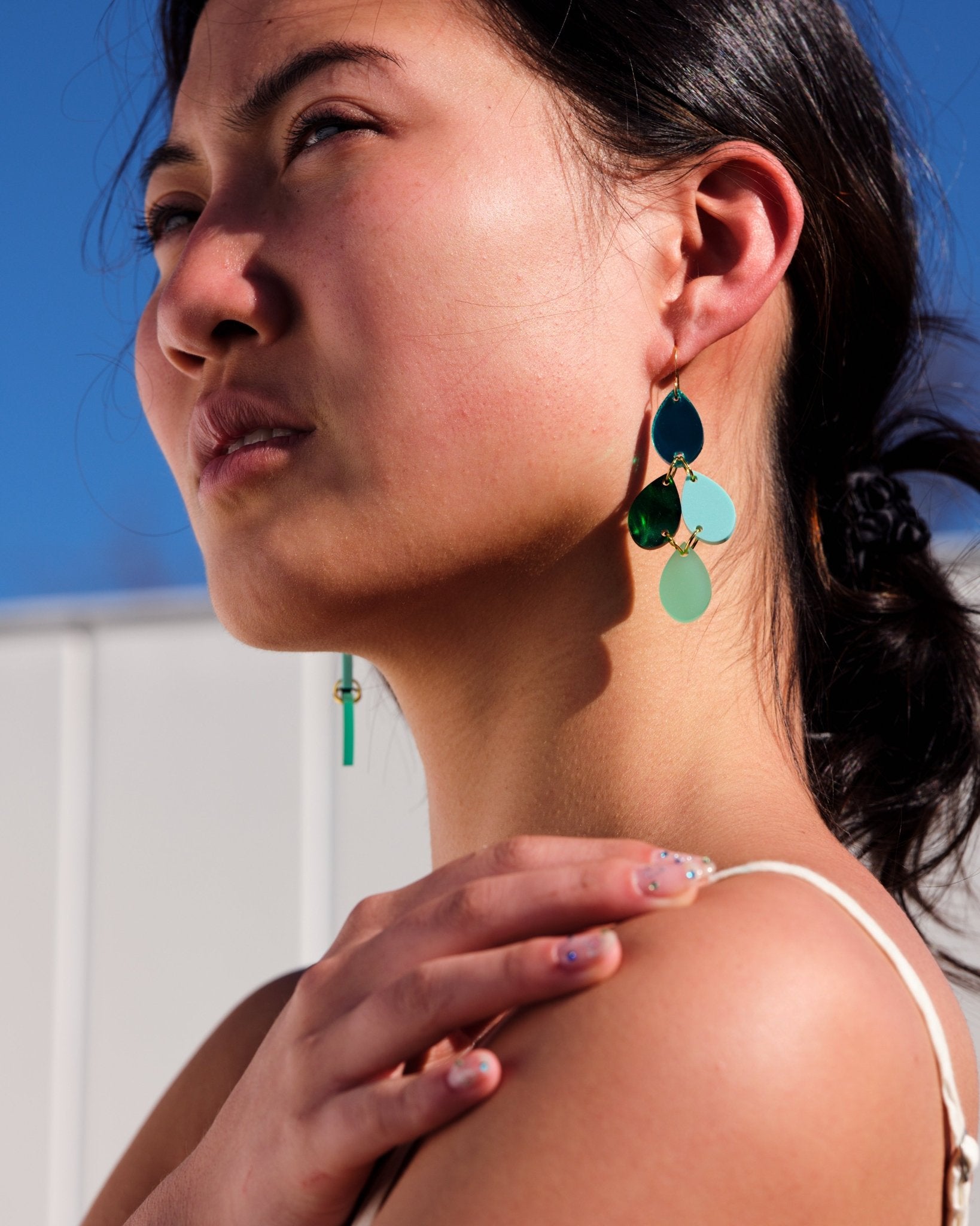 Woman wearing blue and green dangle earrings - ANNIE.G