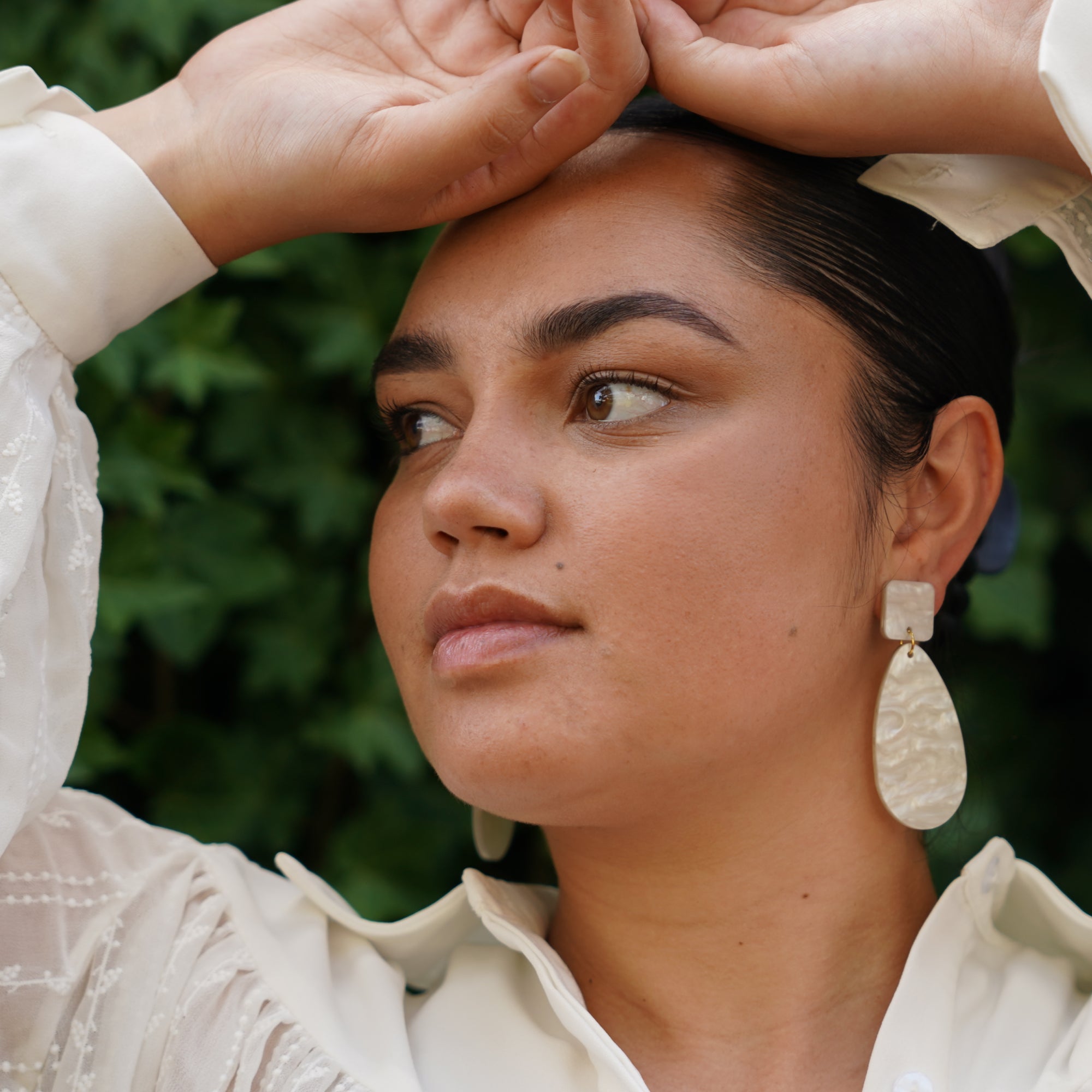 Woman wearing pearl coloured storm earrings.