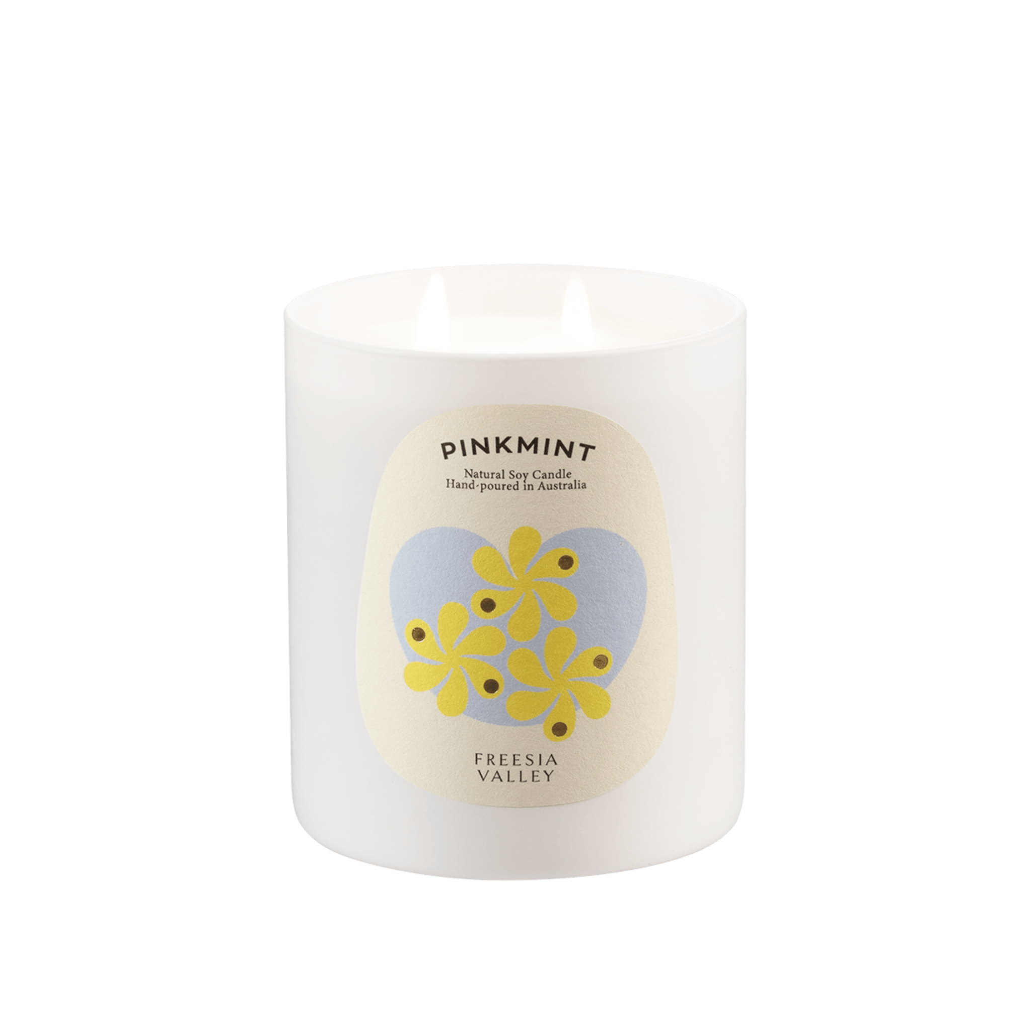 White glass jar with white soy wax candle lit inside and a floral label.