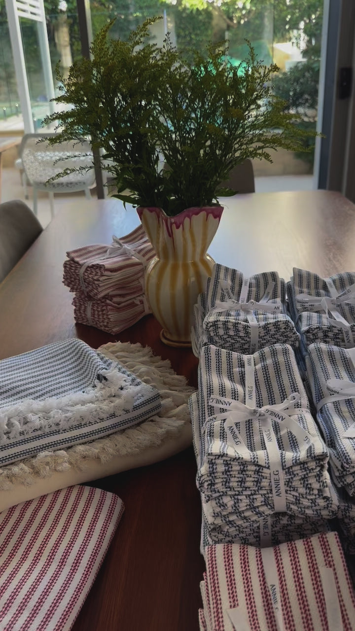 annieg-ticking-napkins-and-square-cotton-tablecloths-folded-and-stacked-on-table-details-movie