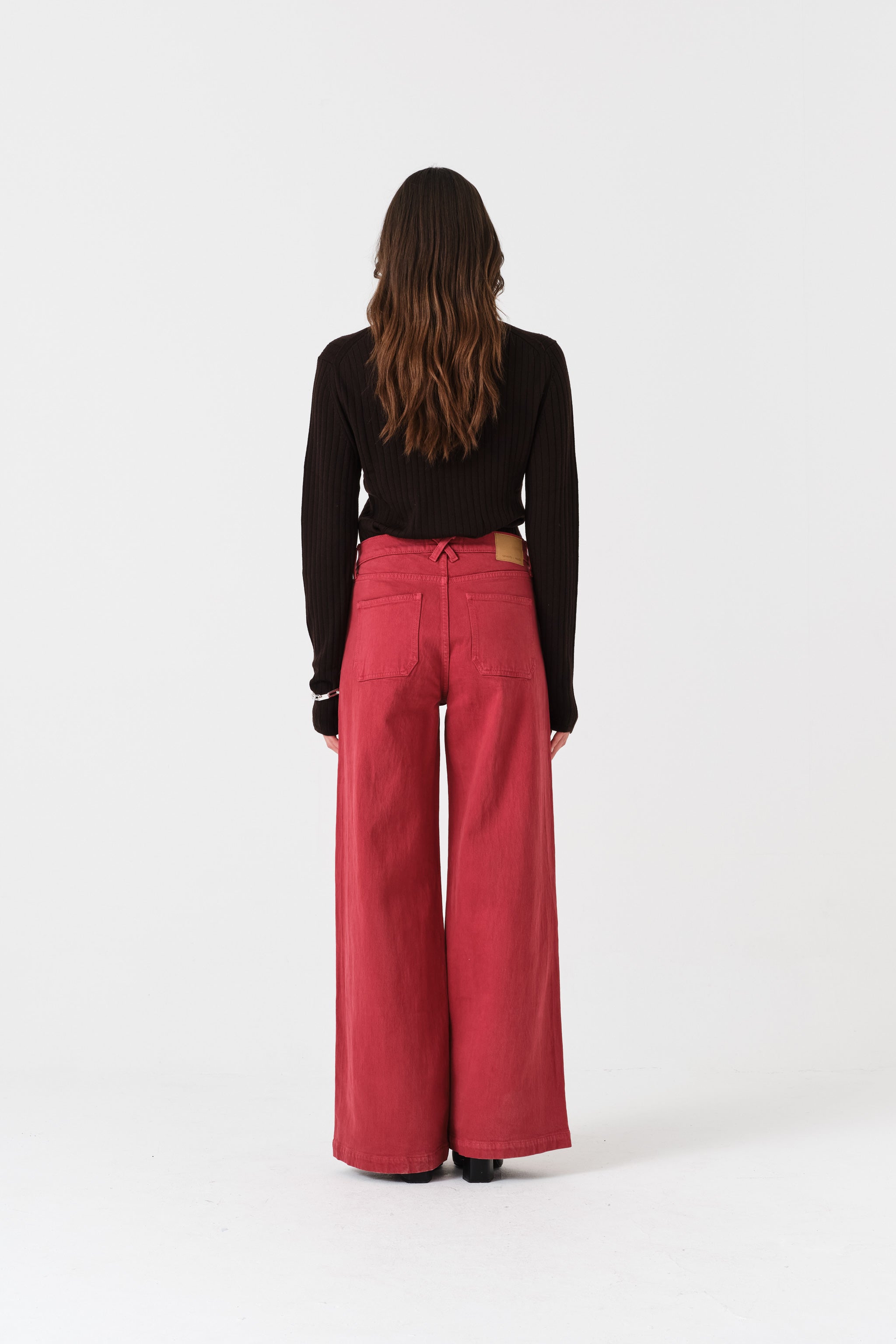 Person wearing faded rose wide-leg denim jeans and a black top.