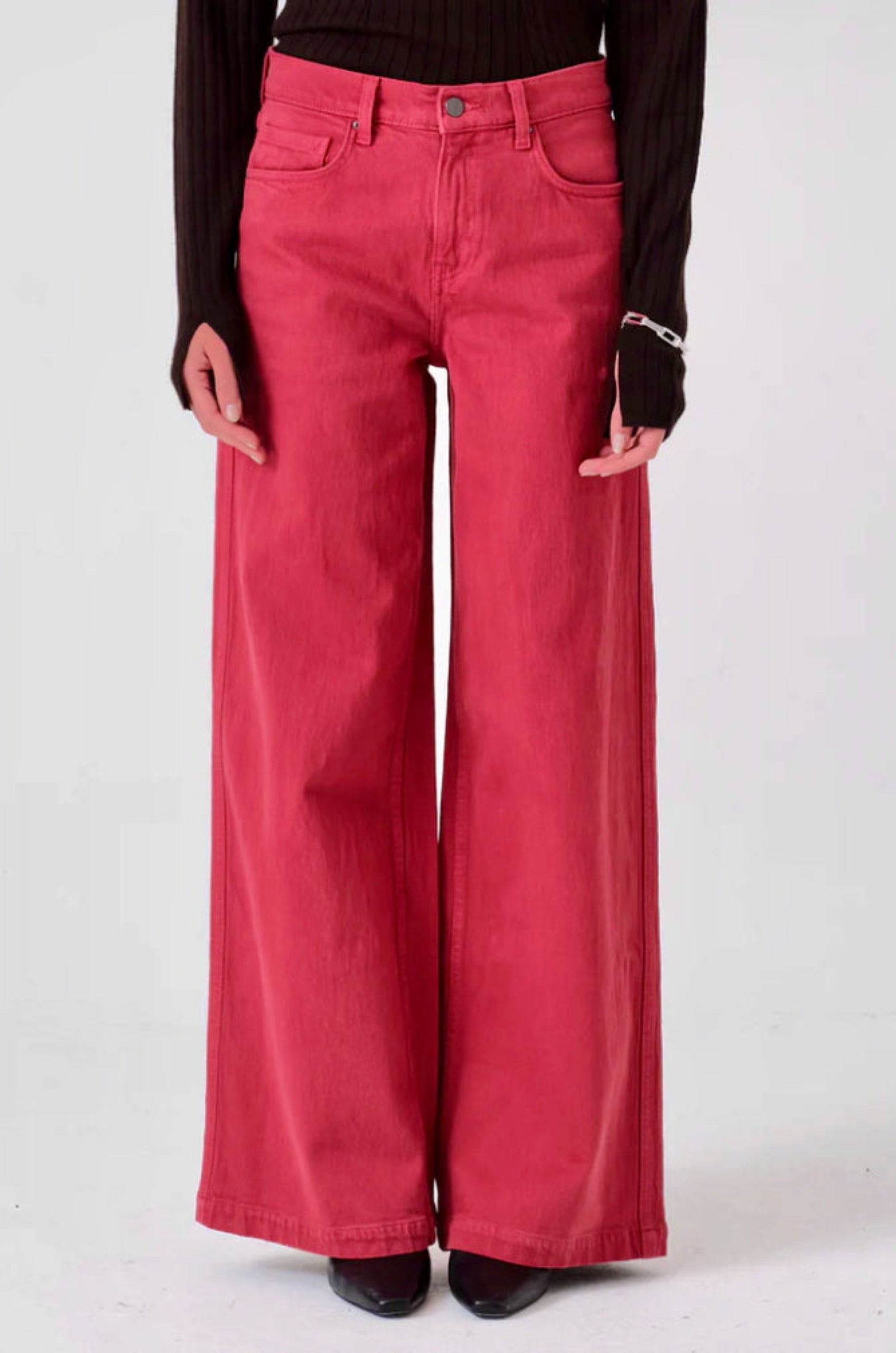 Person wearing faded rose pink wide-leg jeans with pockets, fly zip and button.