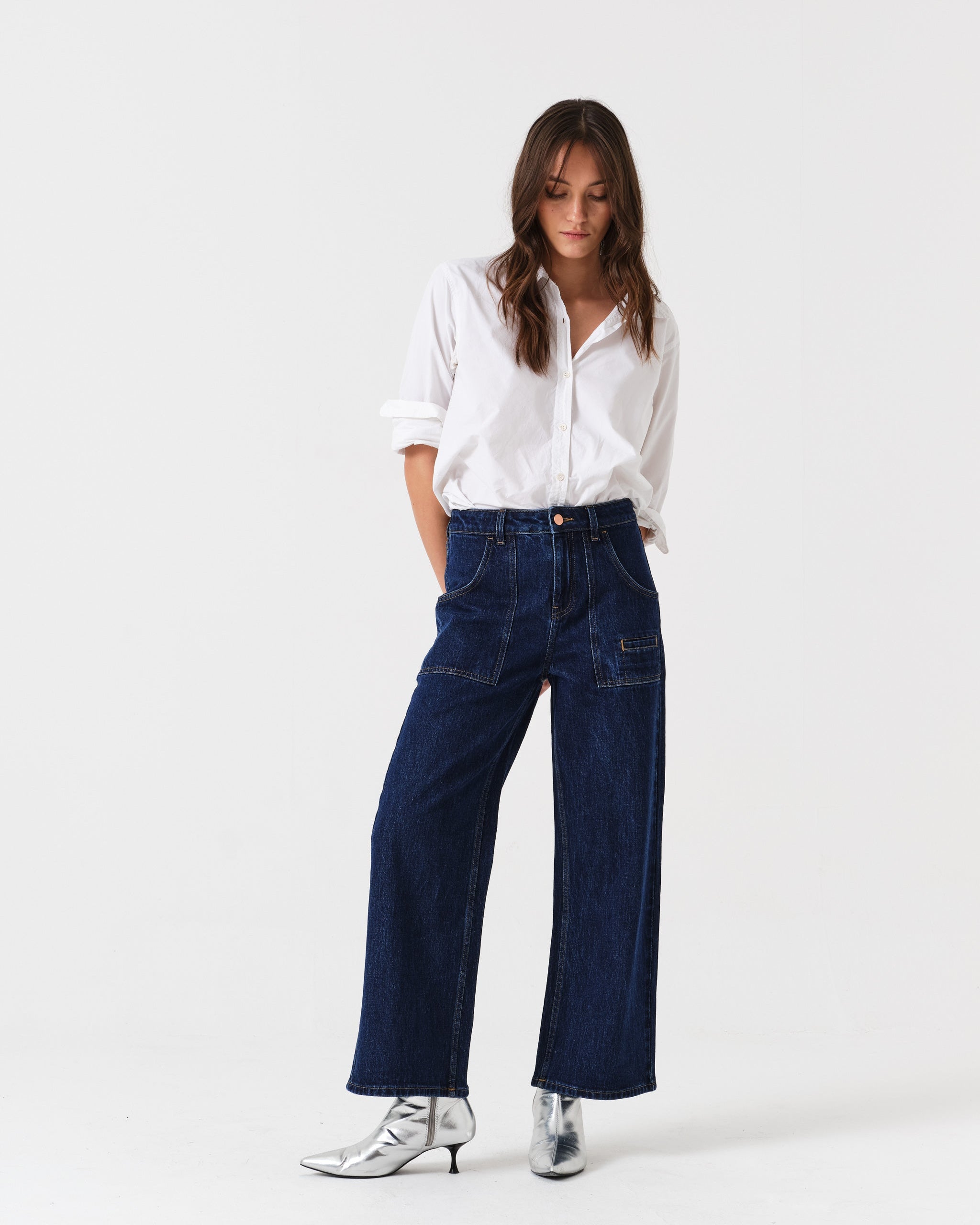Woman wearing a white shirt and blue cropped jeans with patch pockets.