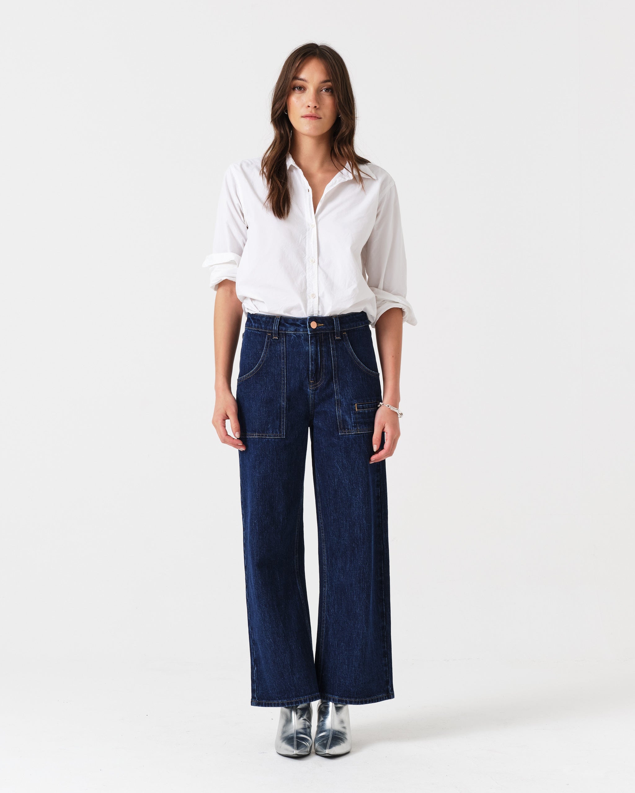 Woman wearing a white shirt and blue cropped jeans with fly zip and pockets.