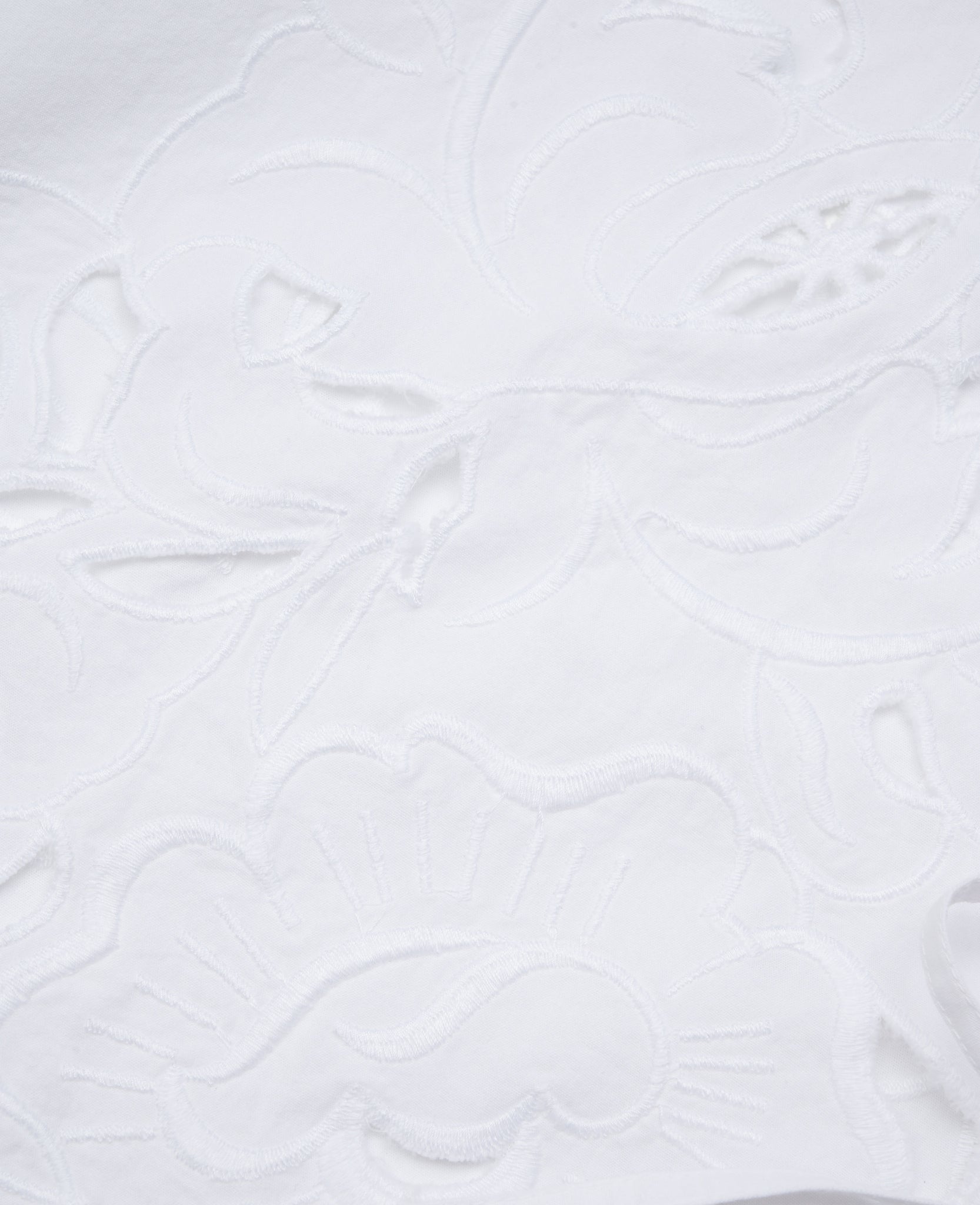 White cutwork embroidery fabric swatch.