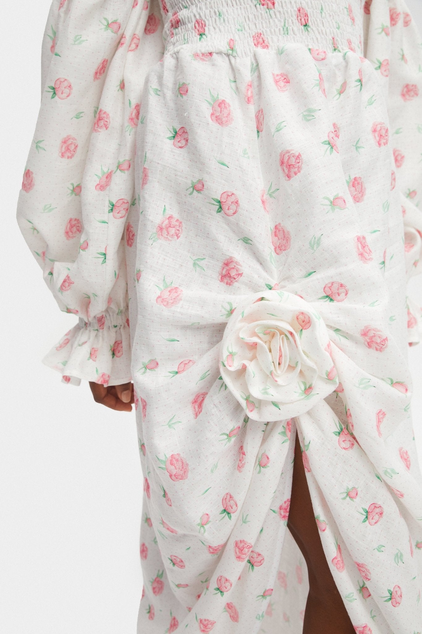 Rosette detail on front slit of white linen rose print dress.