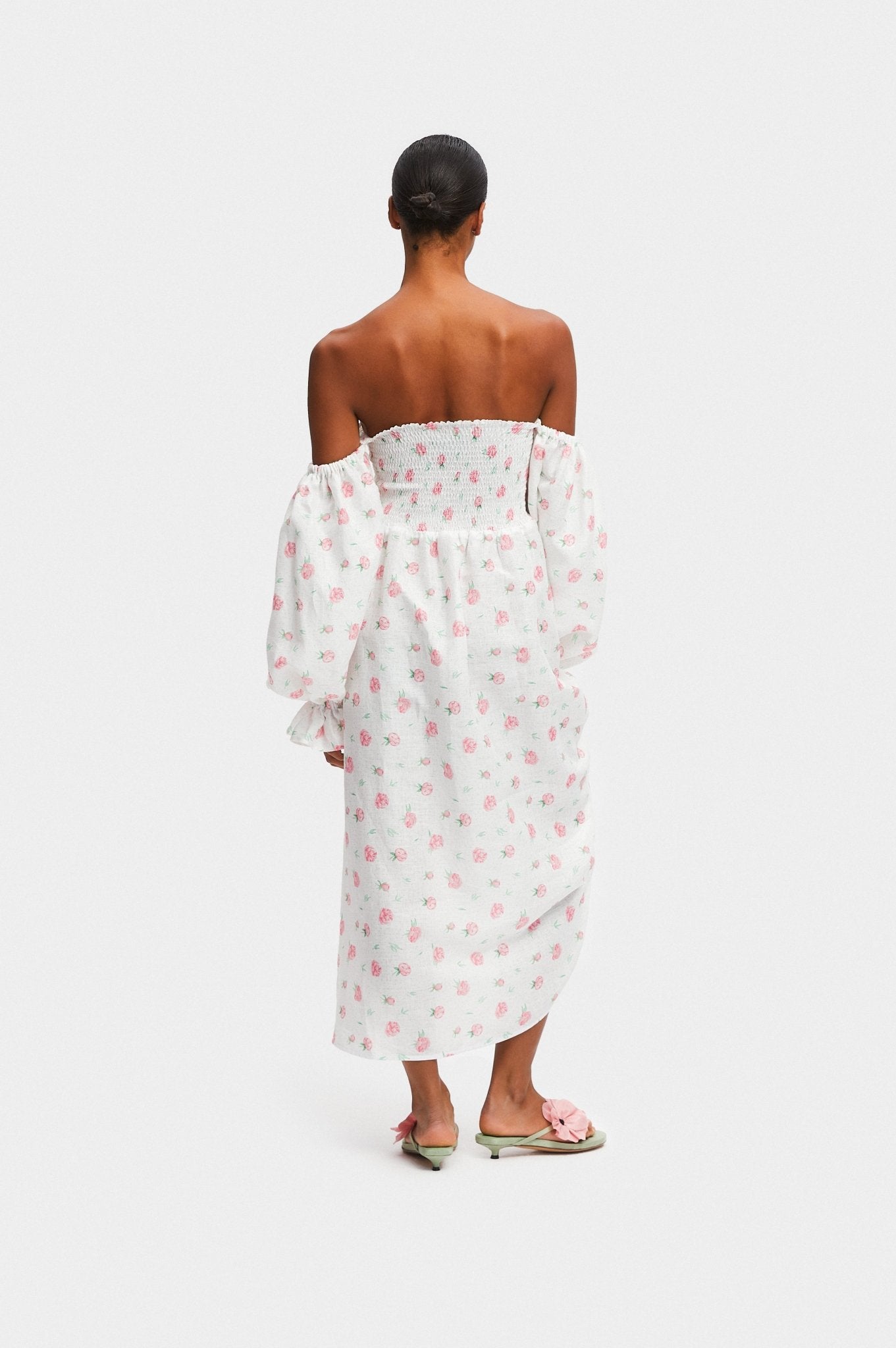 Back of women wearing a long sleeve white linen dress with roses print.