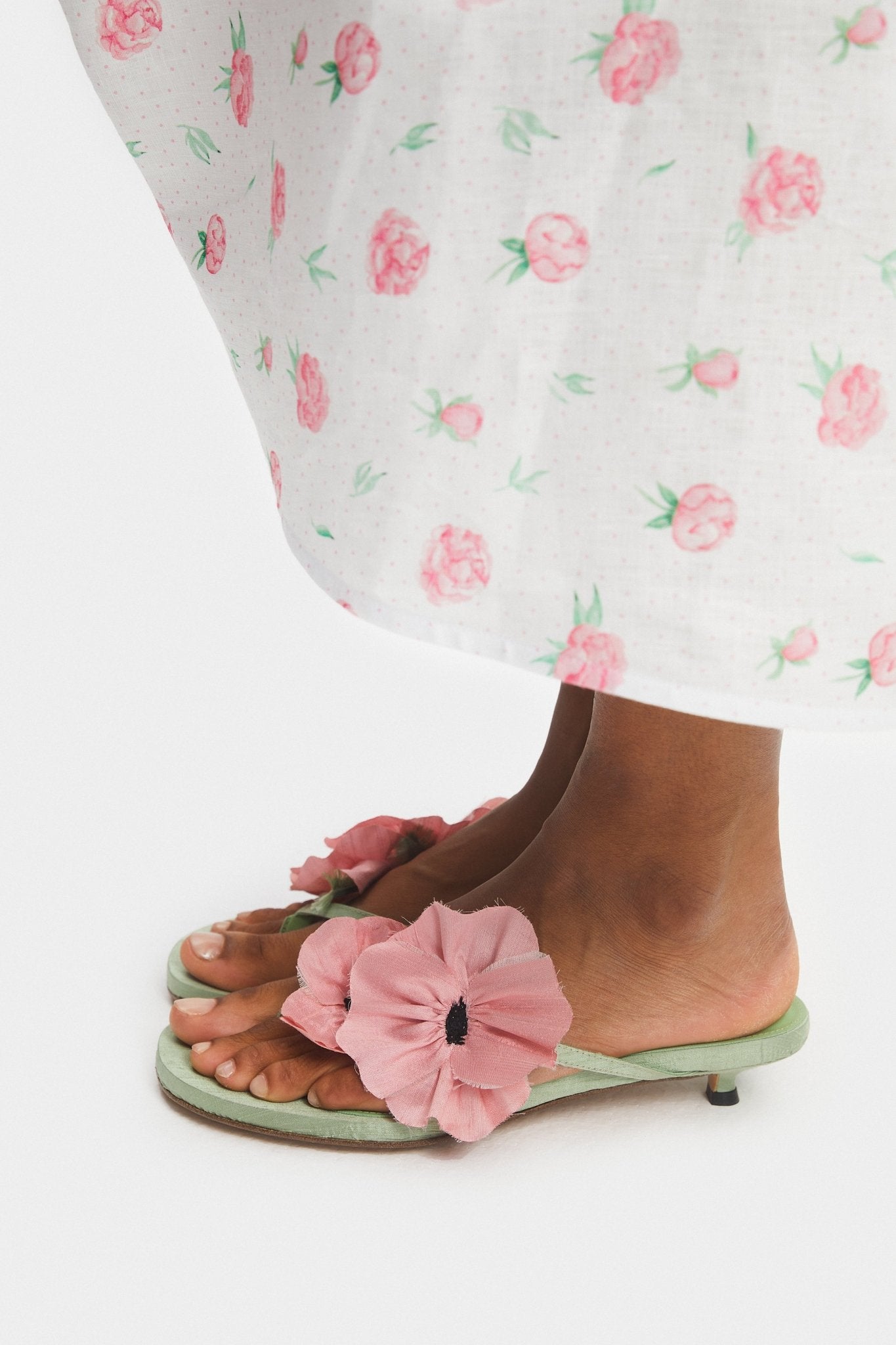 Hem of white linen dress with rose pattern print and poppy shoes.