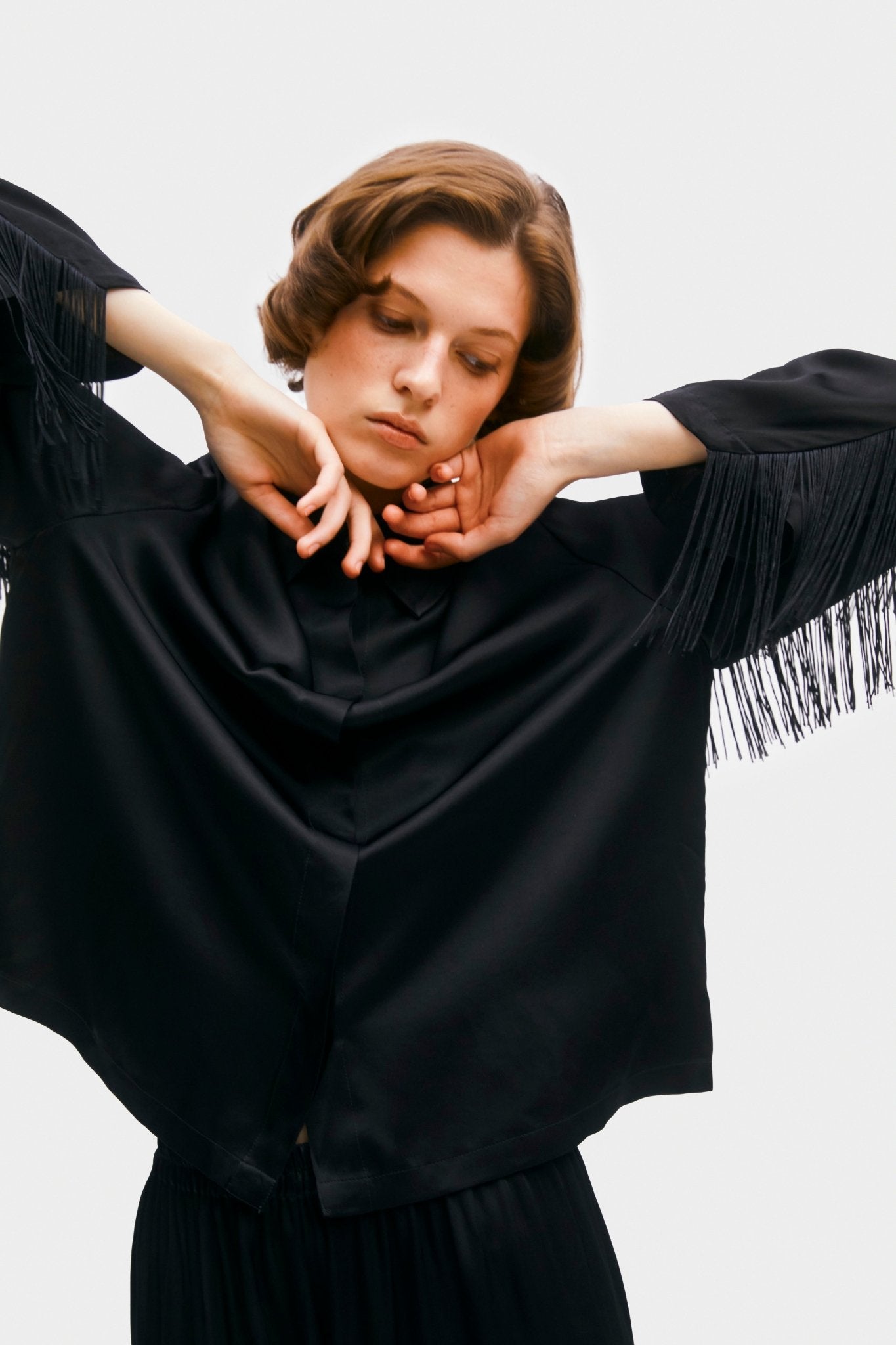 black fringe on sleeve of shirt a woman is wearing and holding arms bent at elbow - ANNIE.G