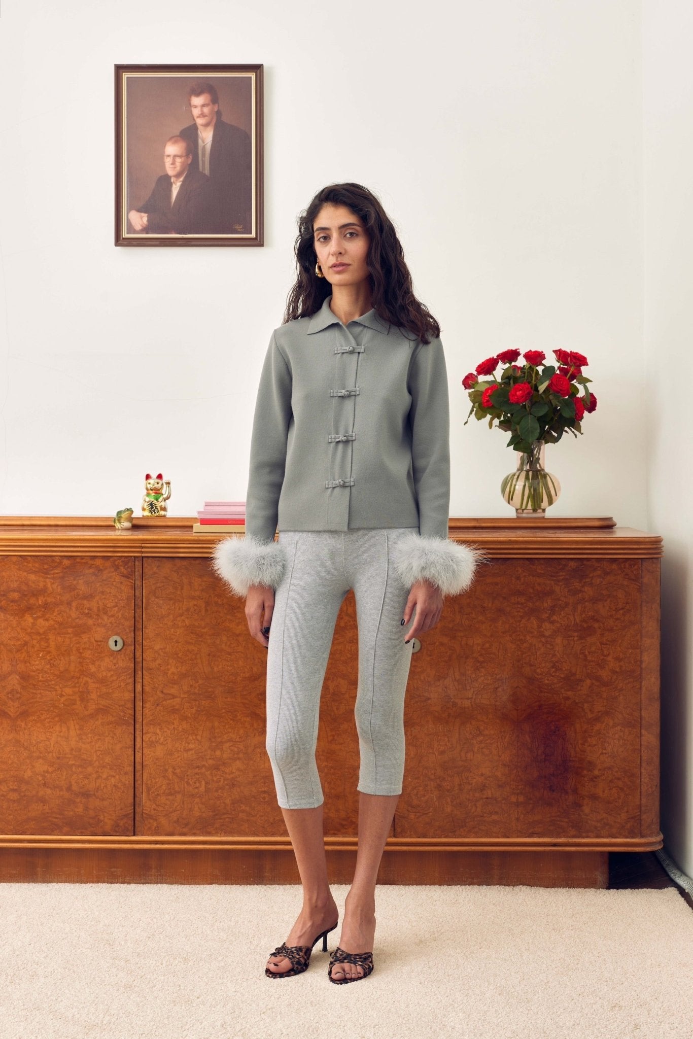 Woman wearing a grey knitted cardigan with Detachable Feathers and front frog fasteners.