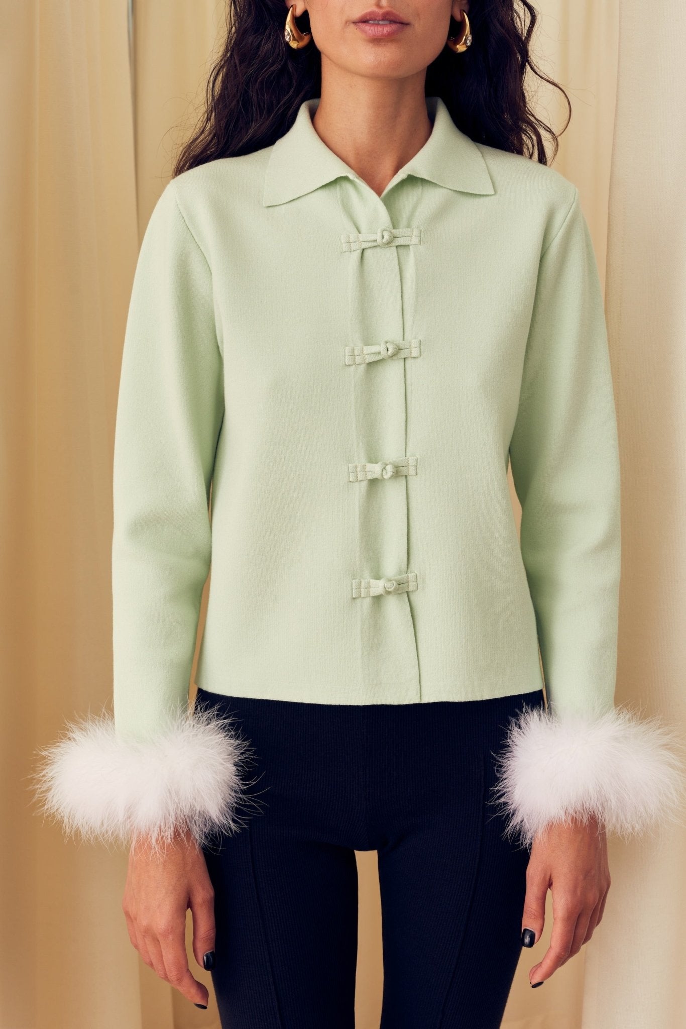 Woman wearing mint Knitted Cardigan with Detachable Feathers and frog tie closure.