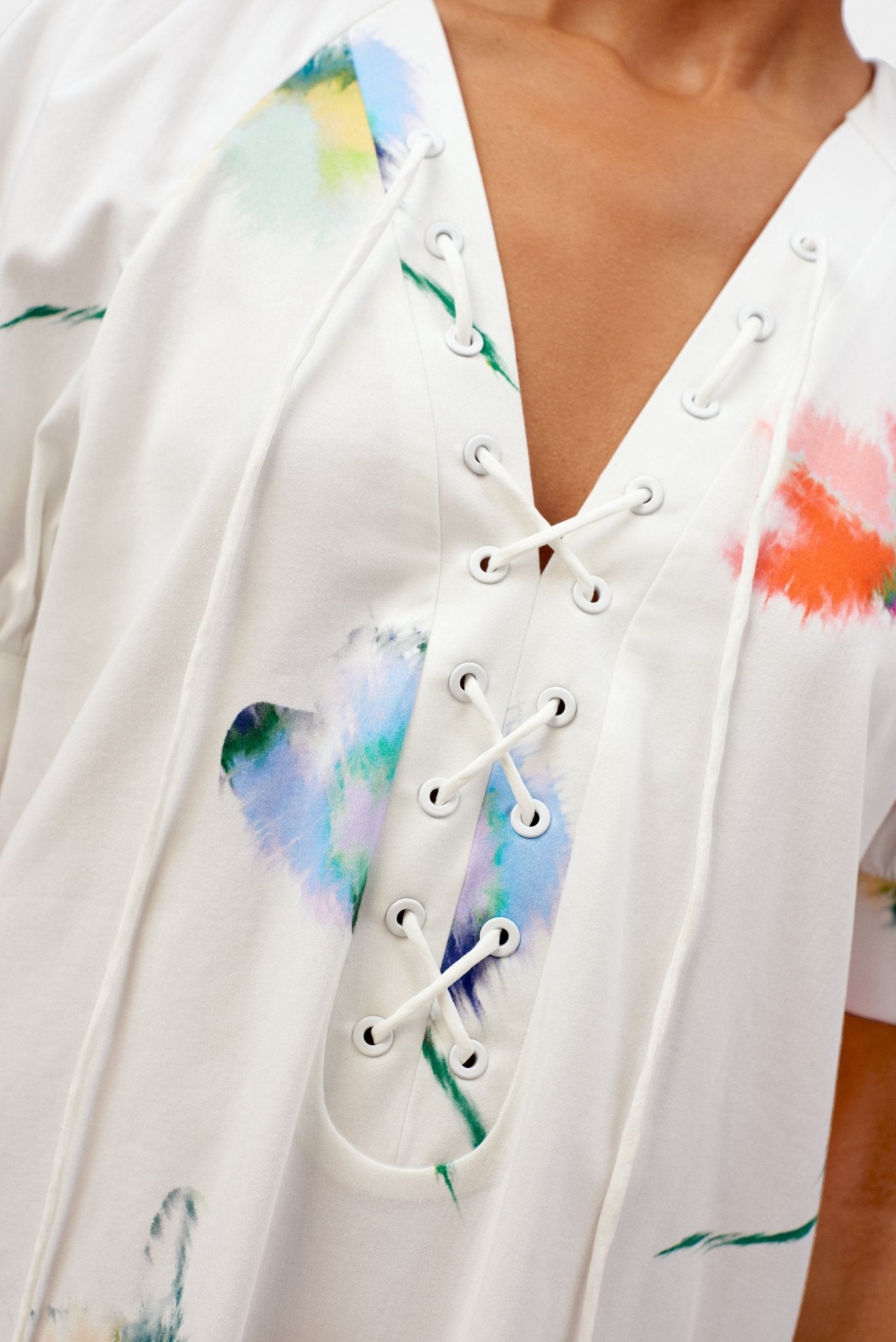 Close up of v-neck lacing details on women's white floral dress.