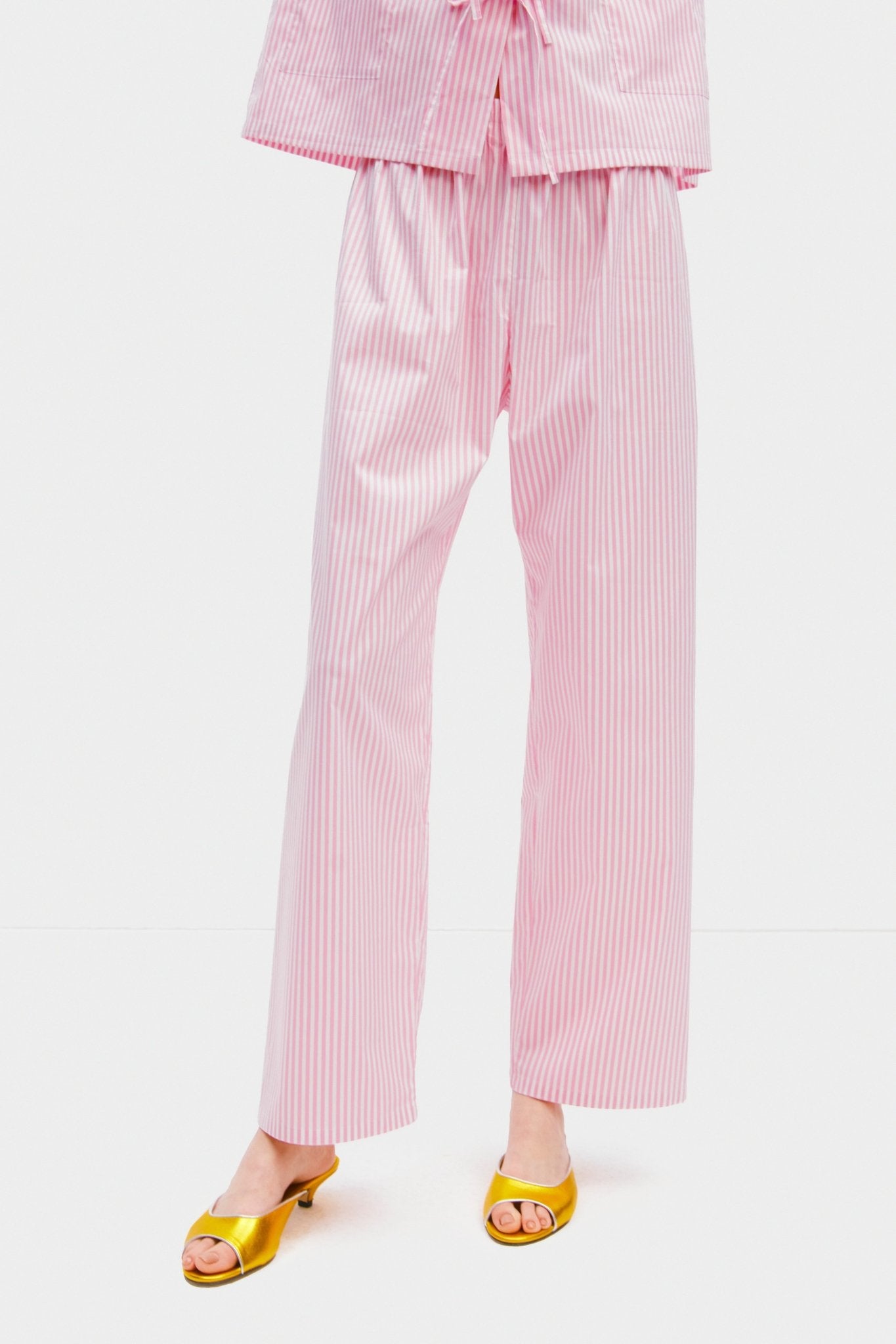 Woman wearing pink stripe long pyjama pants.