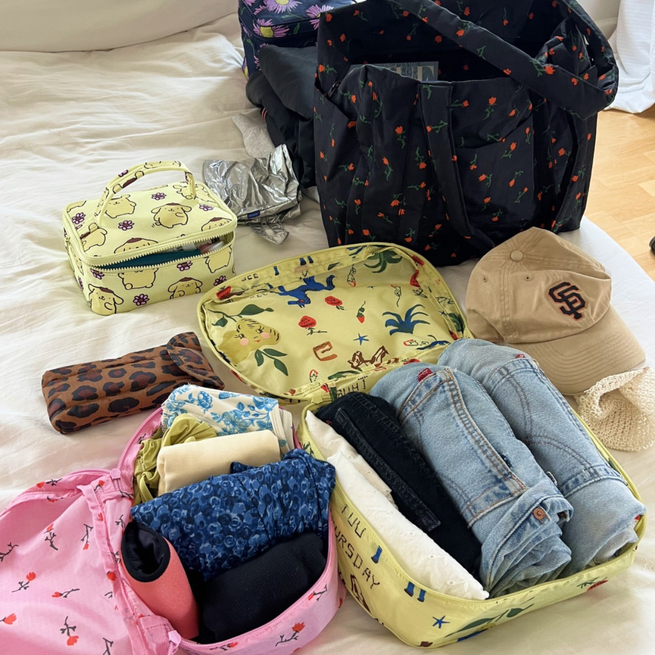 Collection of colourful packing bags and clothing items on a bed