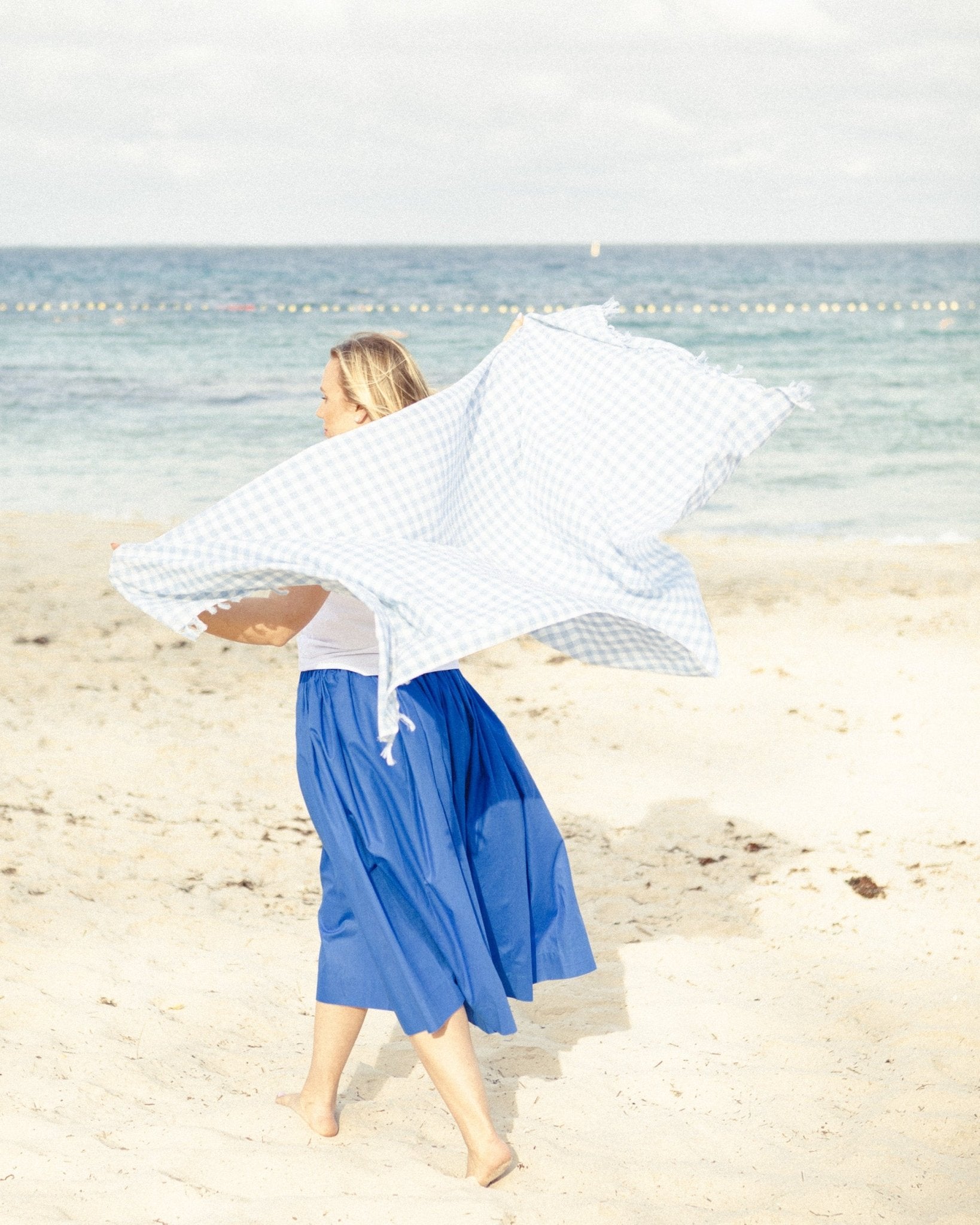 Women walking on beach wrapping towel around her body at beach.