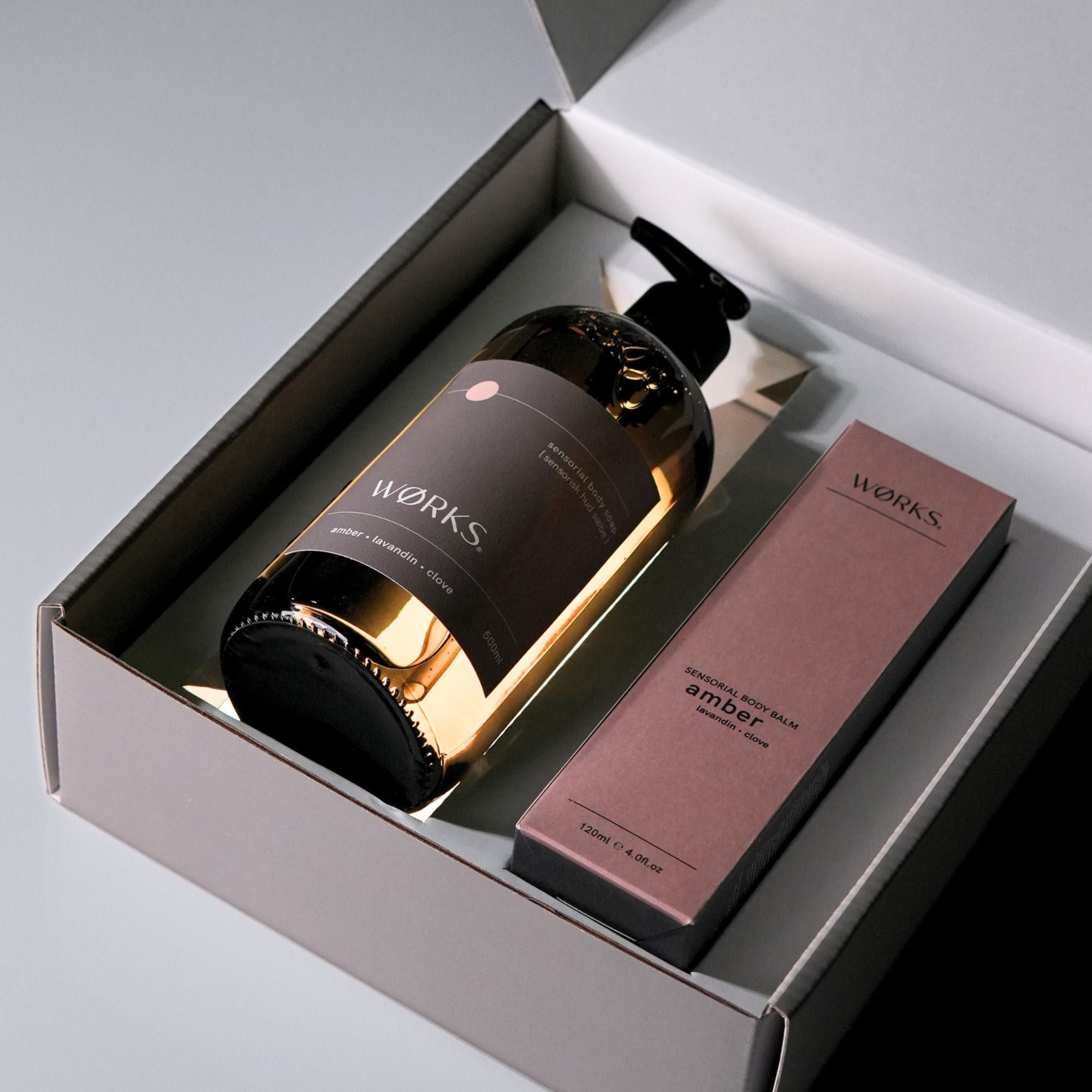 A brown, glass pump bottle and a brown box of 'WORKS' products in a grey gift box with lid open.