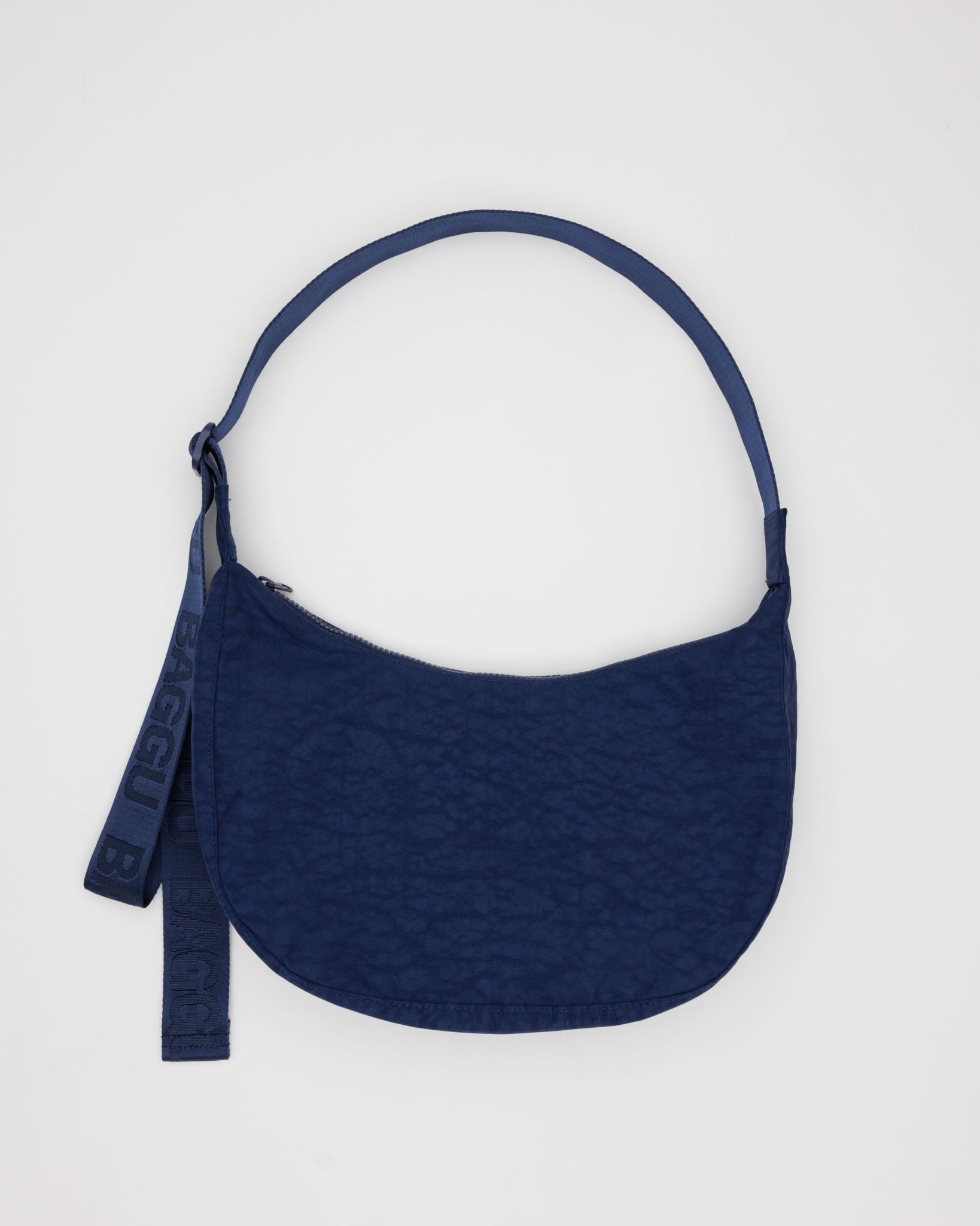 Navy medium crescent bag with adjustable tonal navy strap and zip top.