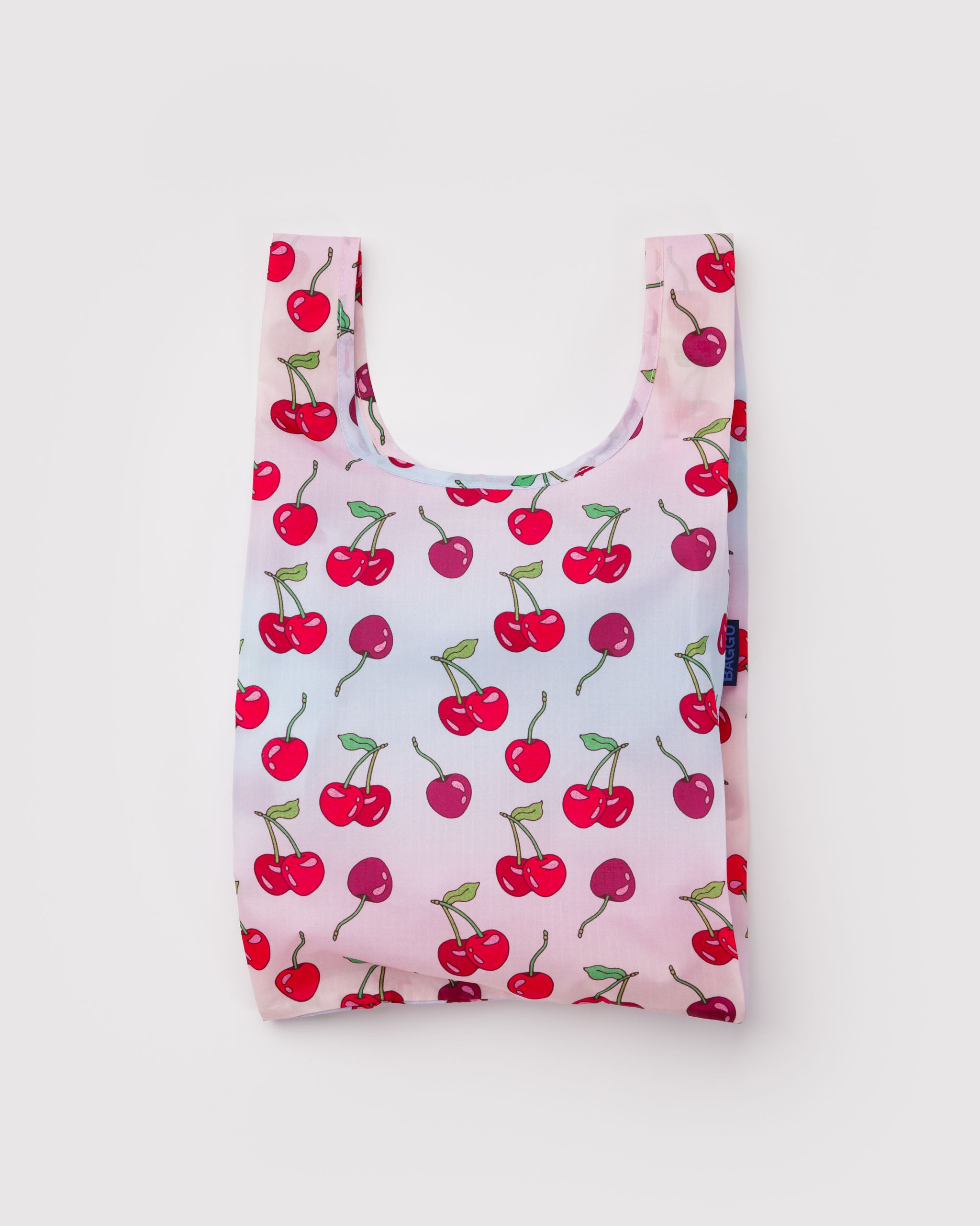 Reusable tote bag with red cherry pattern on a light pink background.