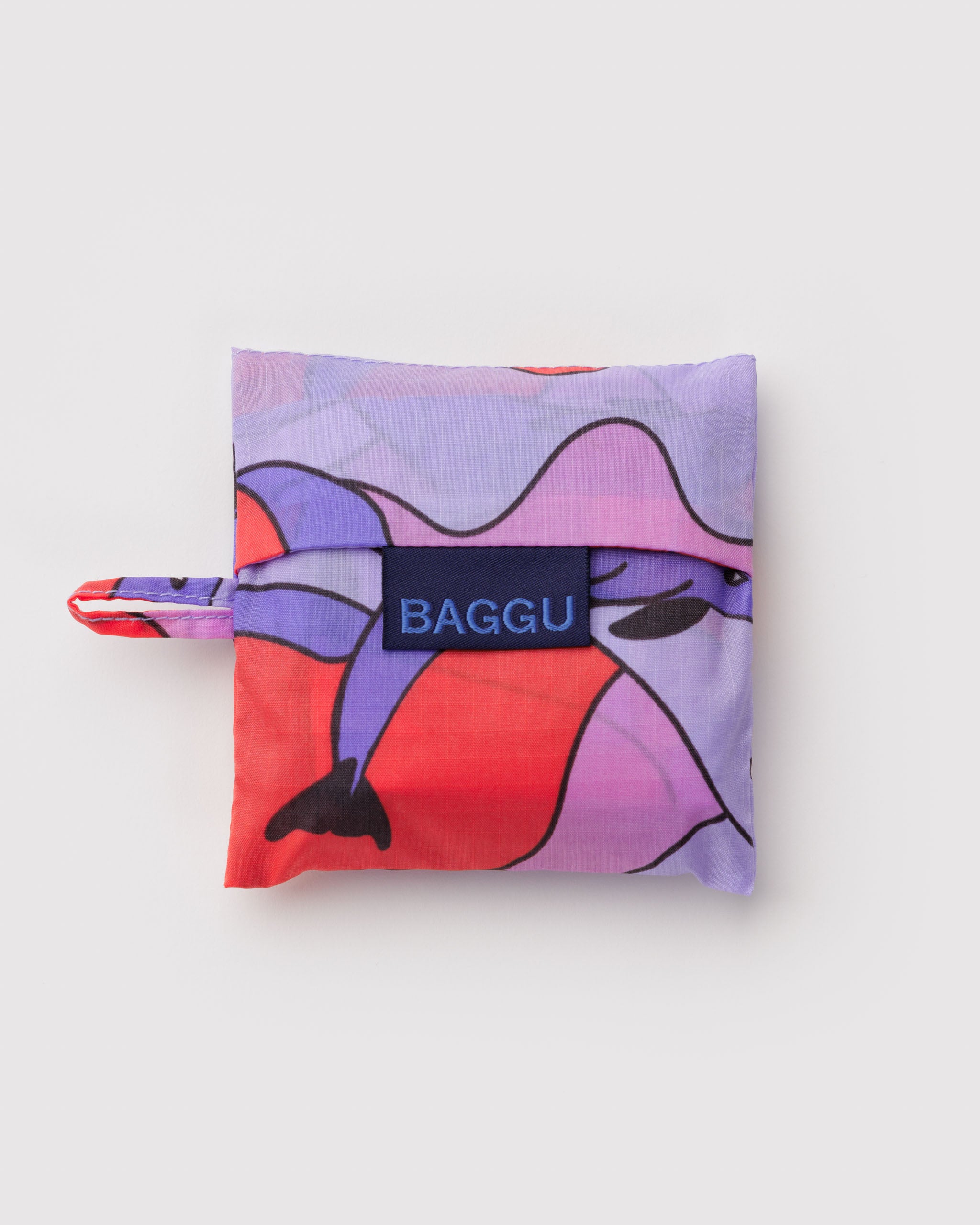 Colourful folded bag with abstract dolphin pattern and 'BAGGU' branding and hanging loop.