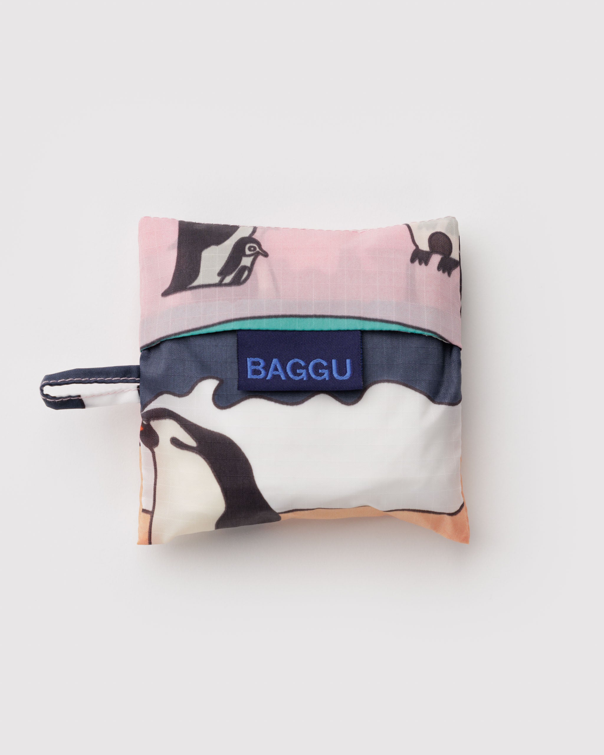 Folded reusable bag with penguin design and 'Baggu' branding with hanging loop.