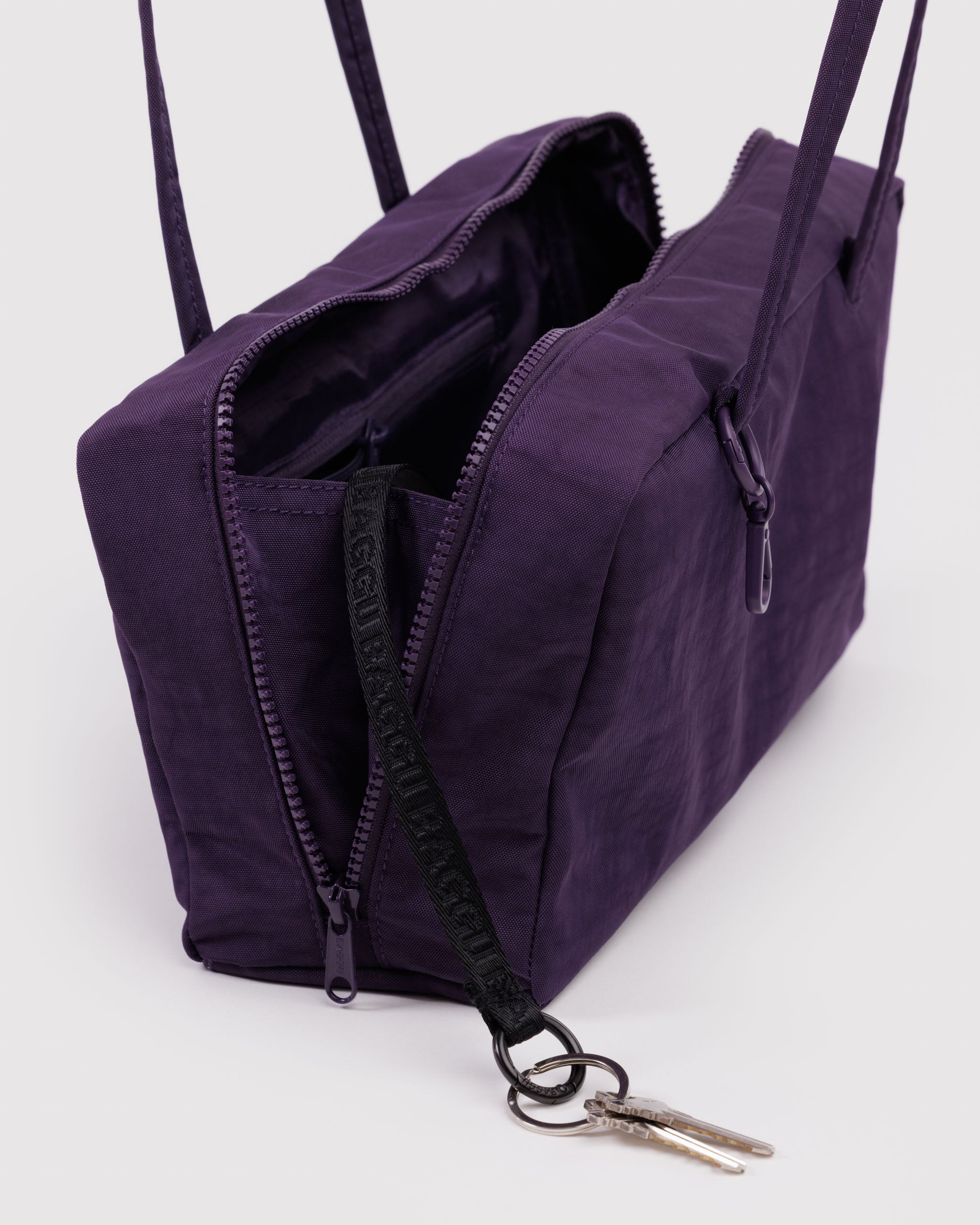 Purple bag with top zippers open and black key leash with keys coming out.