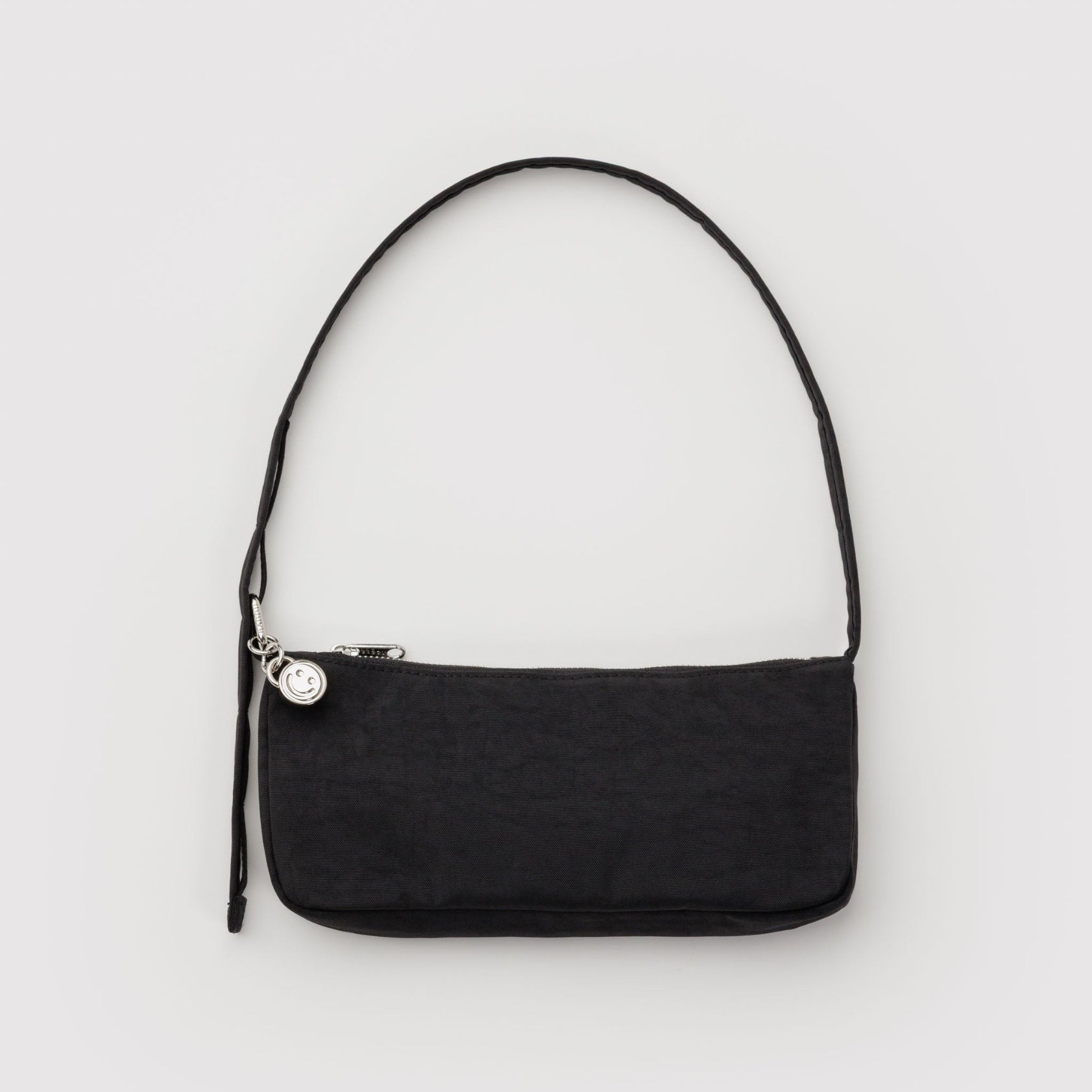 Small black print handbag with adjustable shoulder strap with metal hardware, clasp, zip and smiley face charm.