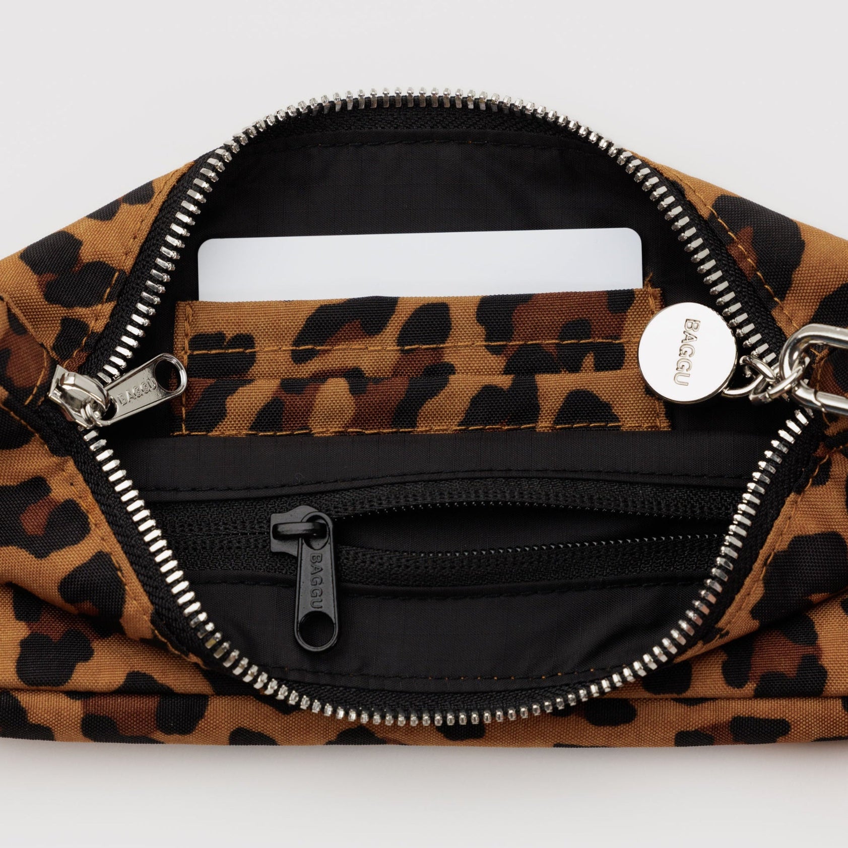 Small leopard print bag with top open zipper and internal zip pocket and card slots with adjustable metal clasp for shoulder strap and charm.