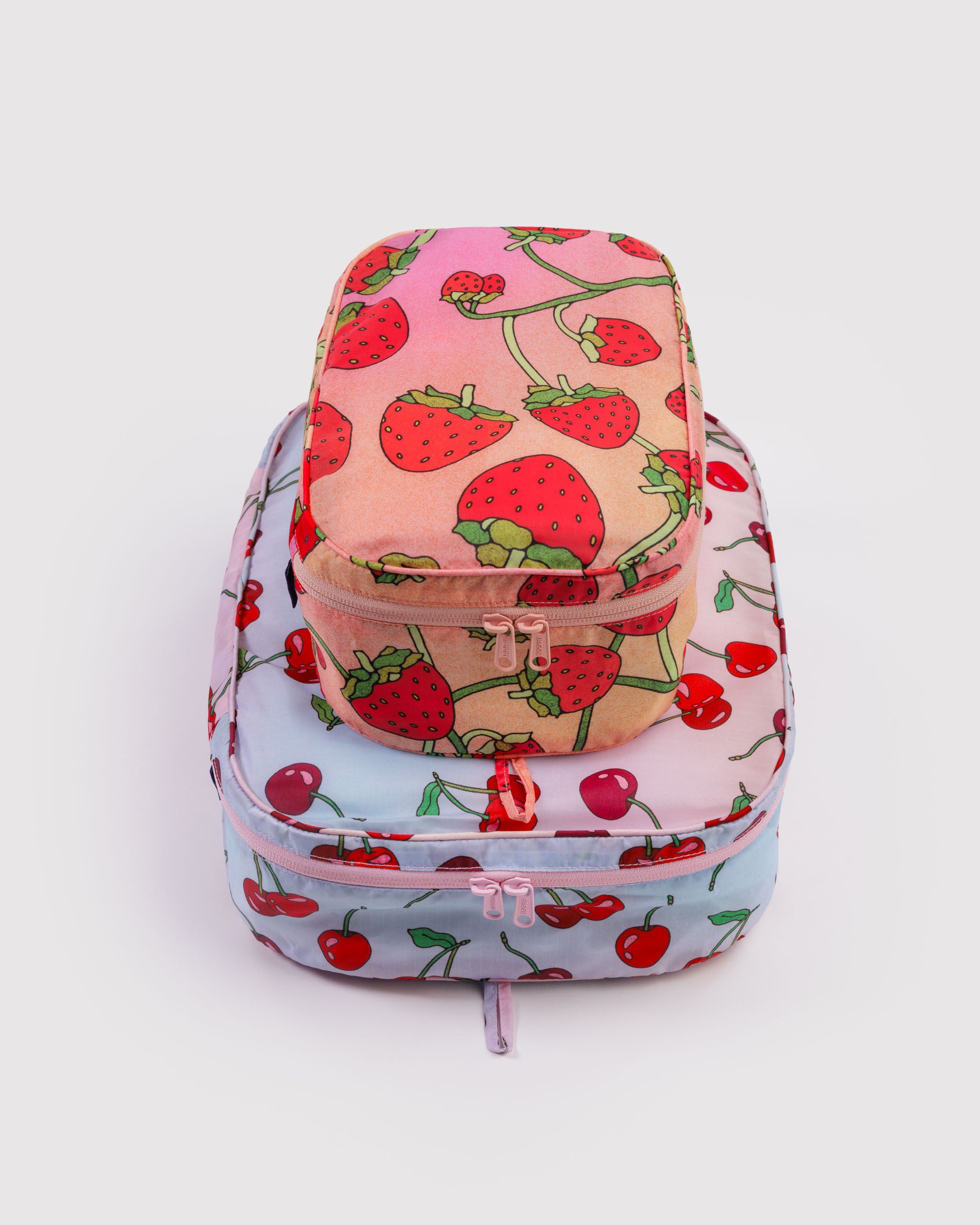 Strawberries and cherries prints on travel packing cubes set in small and medium size with all around tonal zippers.