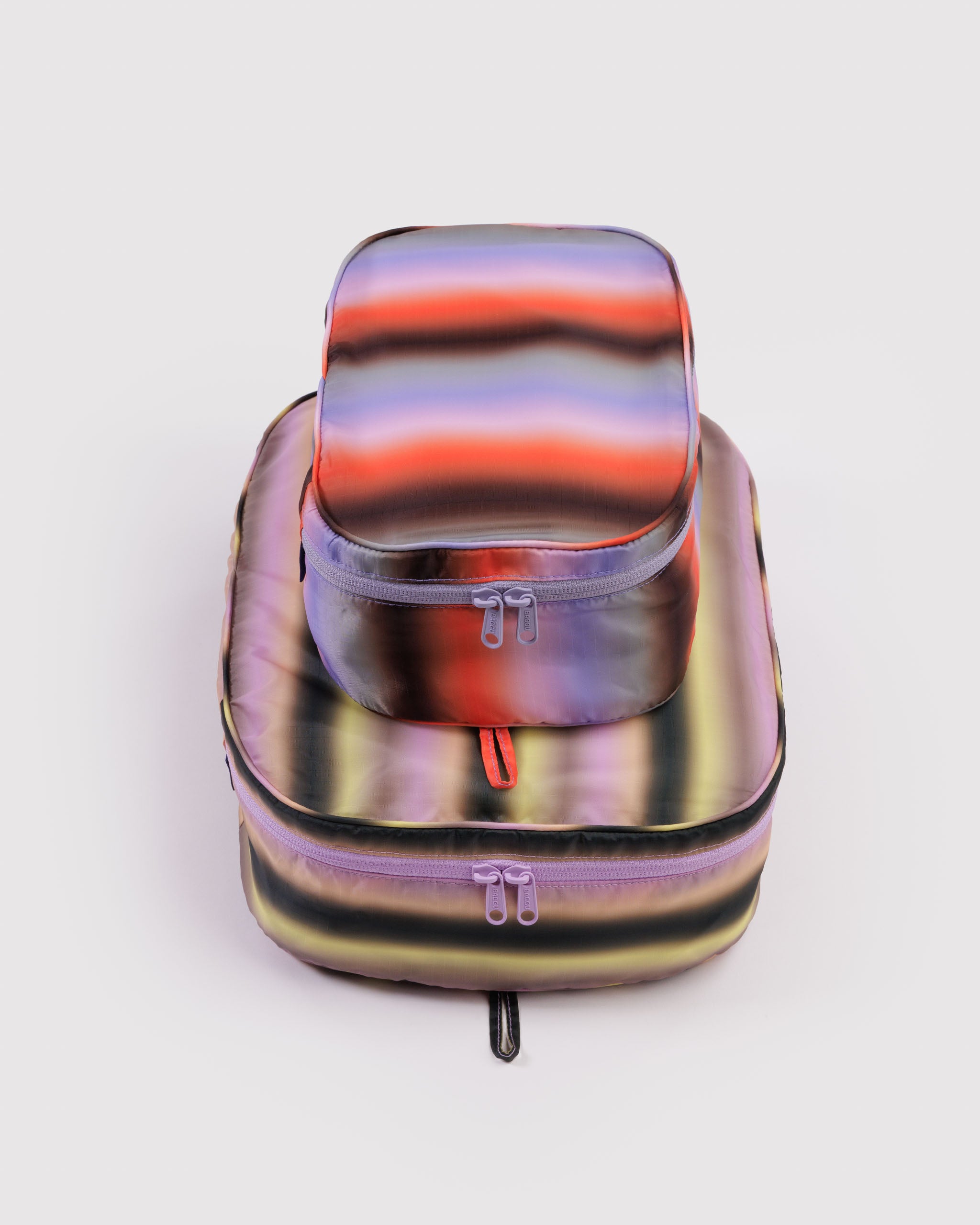 Multicolored stripe print travel packing cubes set in small and medium size with all around tonal zippers.