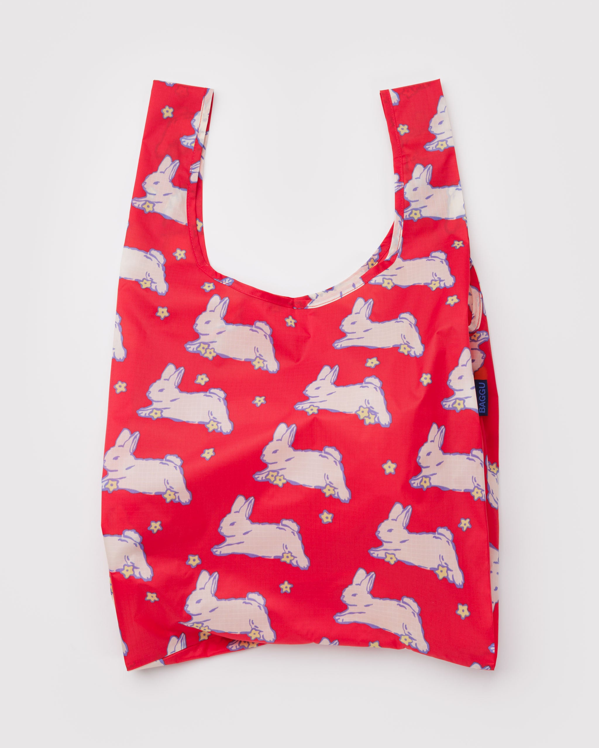 Red reusable tote bag with white bunnies and small yellow flowers pattern.