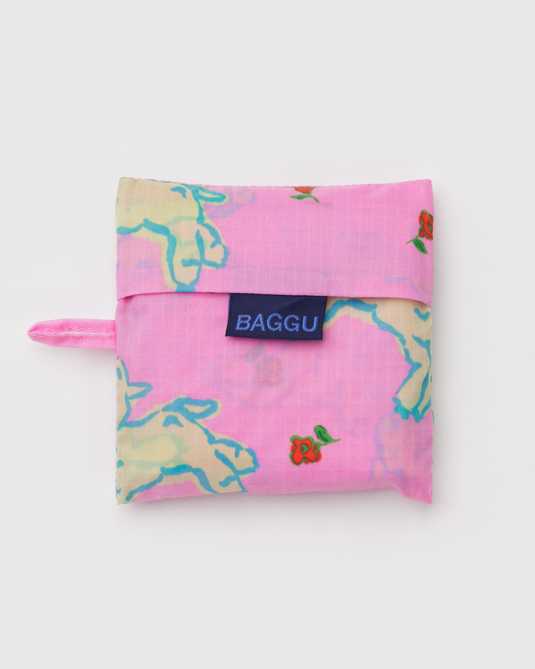 Pink reusable bag with white lambs and a red floral pattern, a blue 'BAGGU' logo and hanging loop.