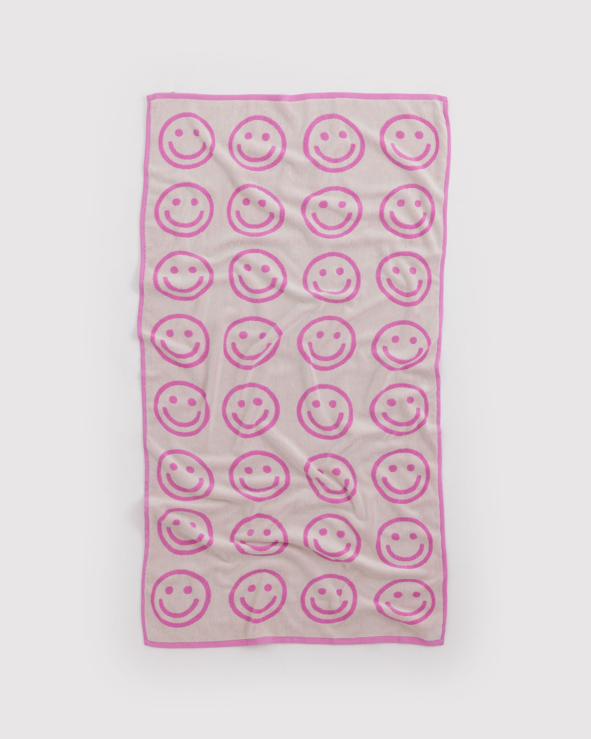 Pink towel with pink smiley face pattern that's reversible.