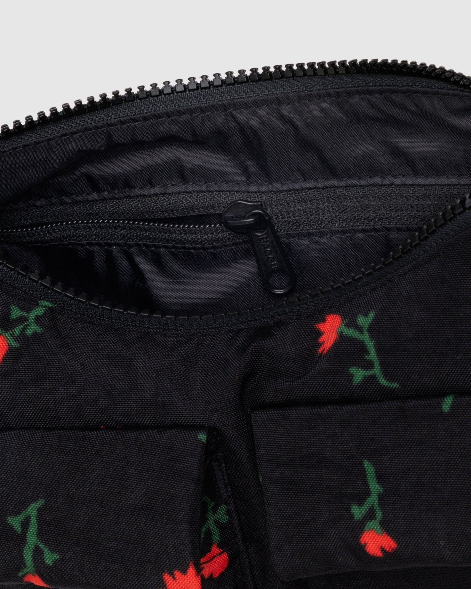 Inside zip pocket, top zip and outside cargo pockets of black shoulder bag with red wildflower pattern