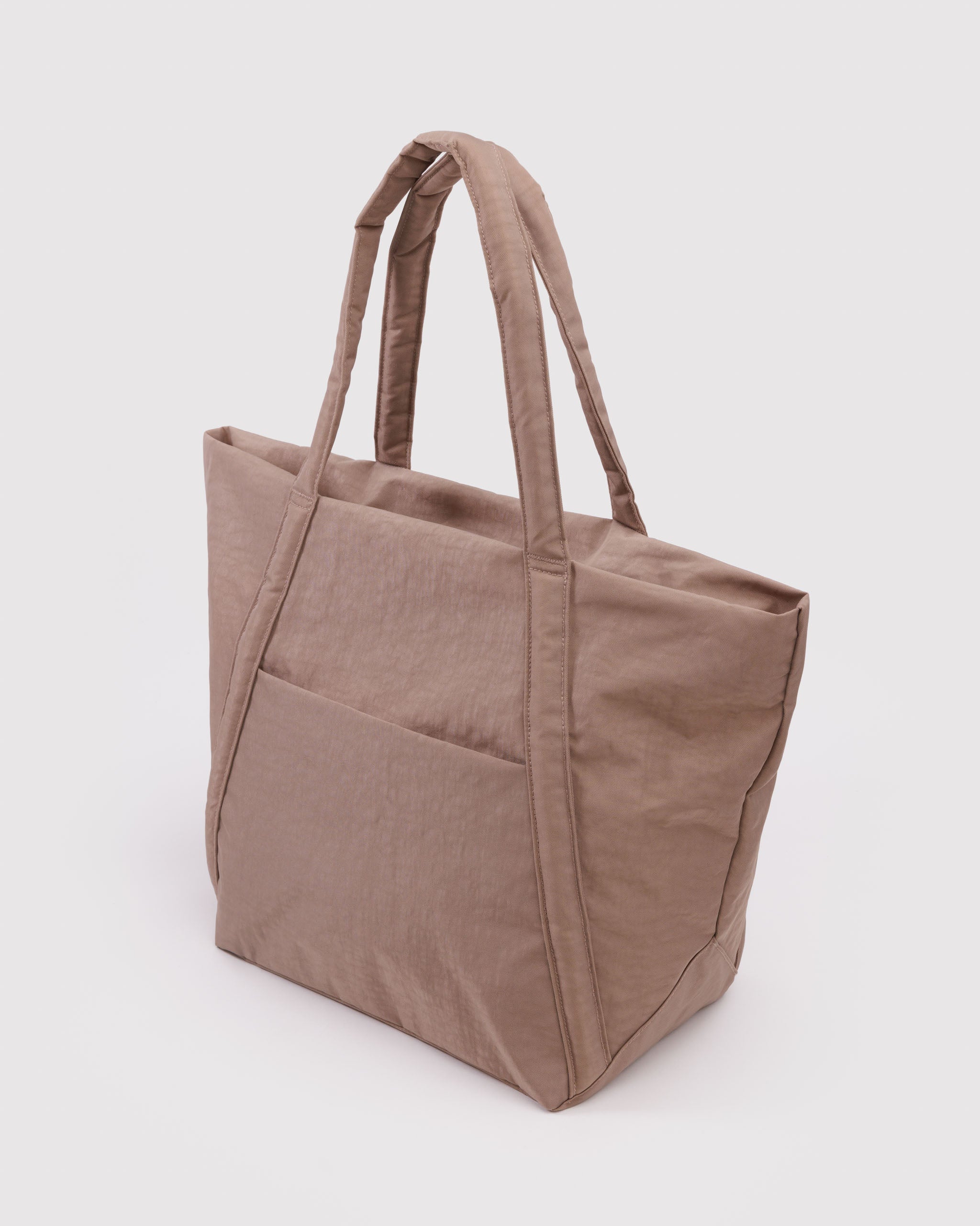 Side view of a light brown hobo tote bag in trapezoid shape.