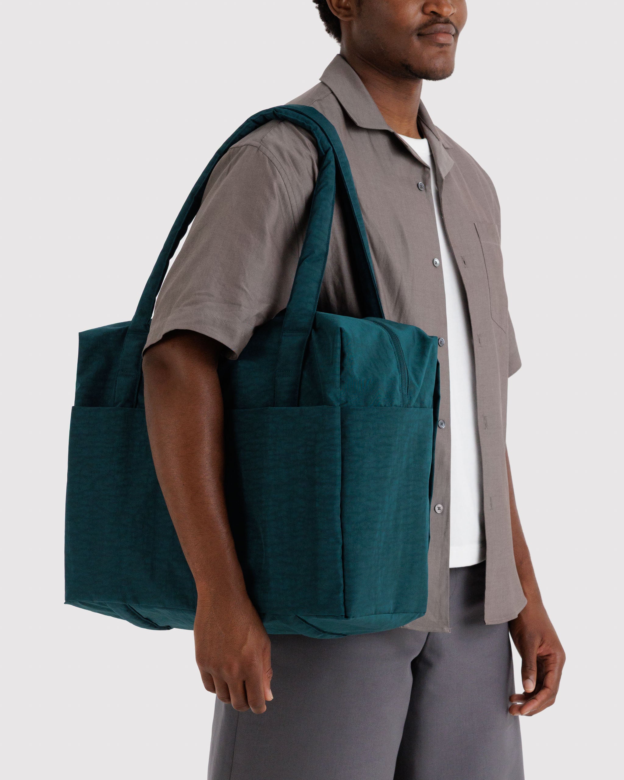 Man carrying a teal tote bag on shoulder.